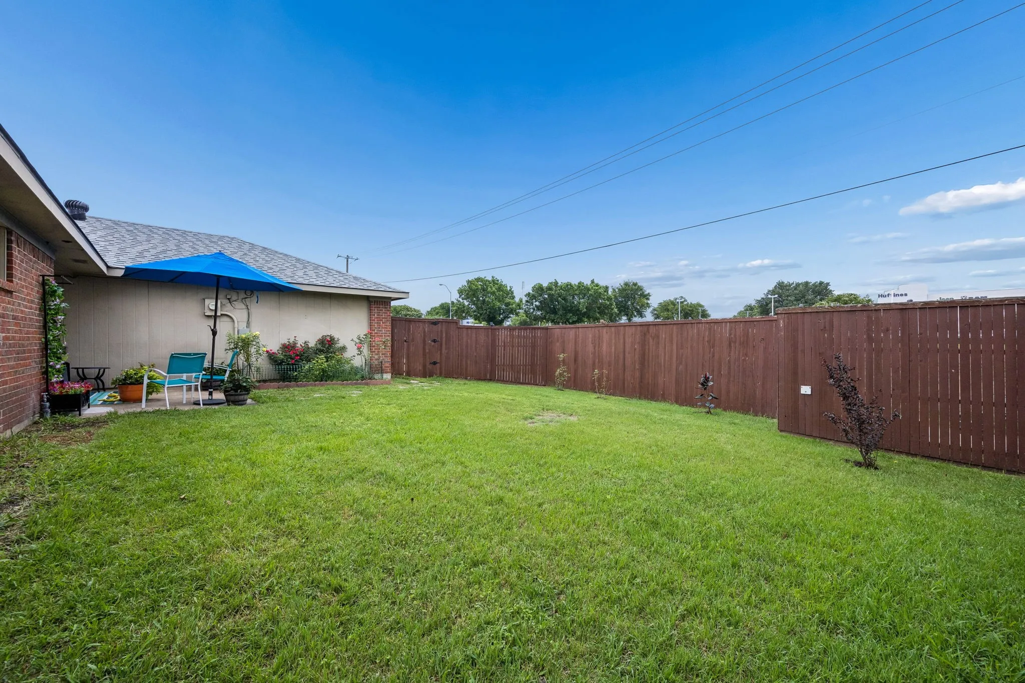 Expansive backyard featuring a wood privacy fence, a concrete patio, and mature landscaping
