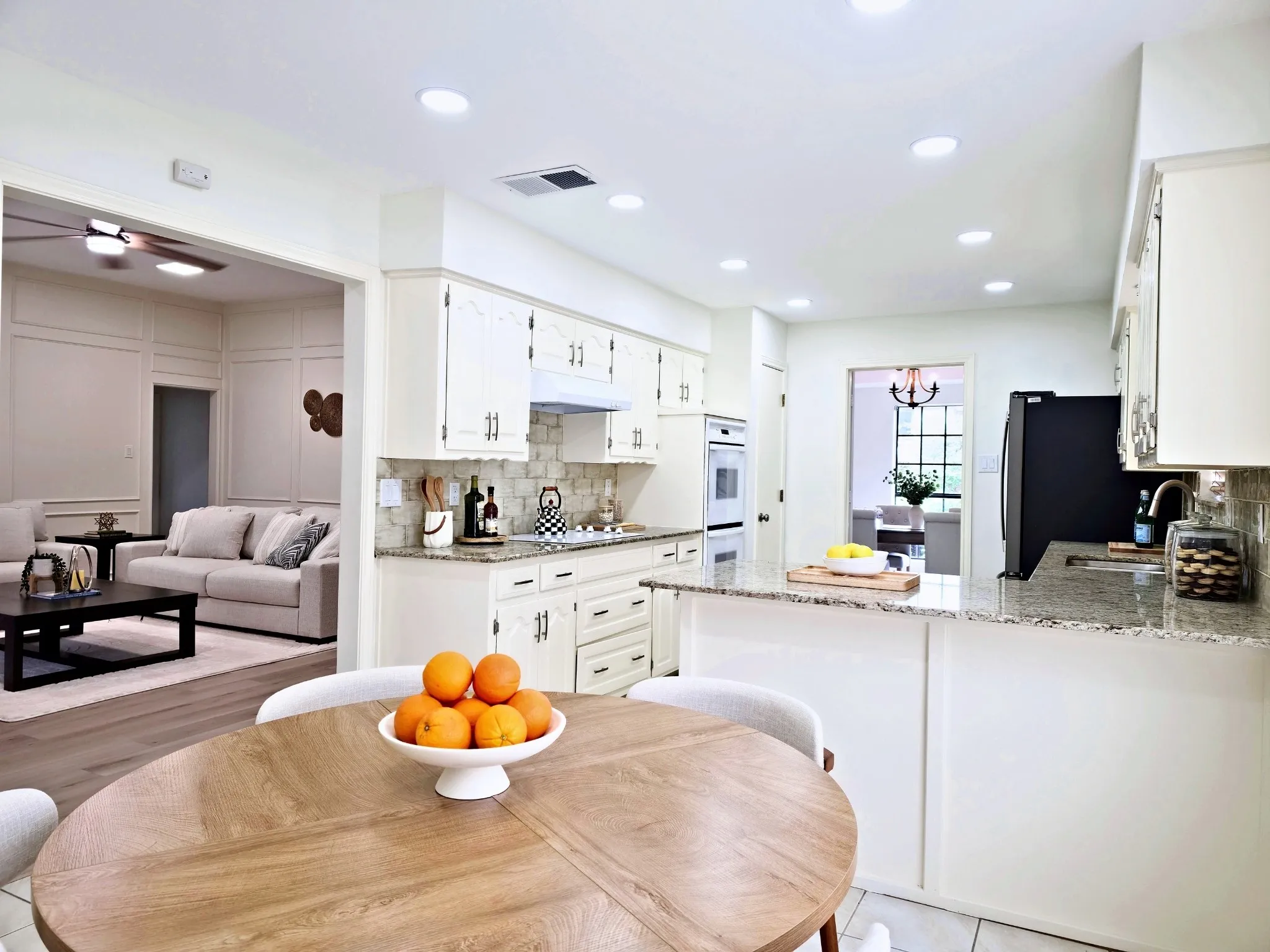 Kitchen with white cabinetry, light-colored granite countertops, and a subway tile backsplash
