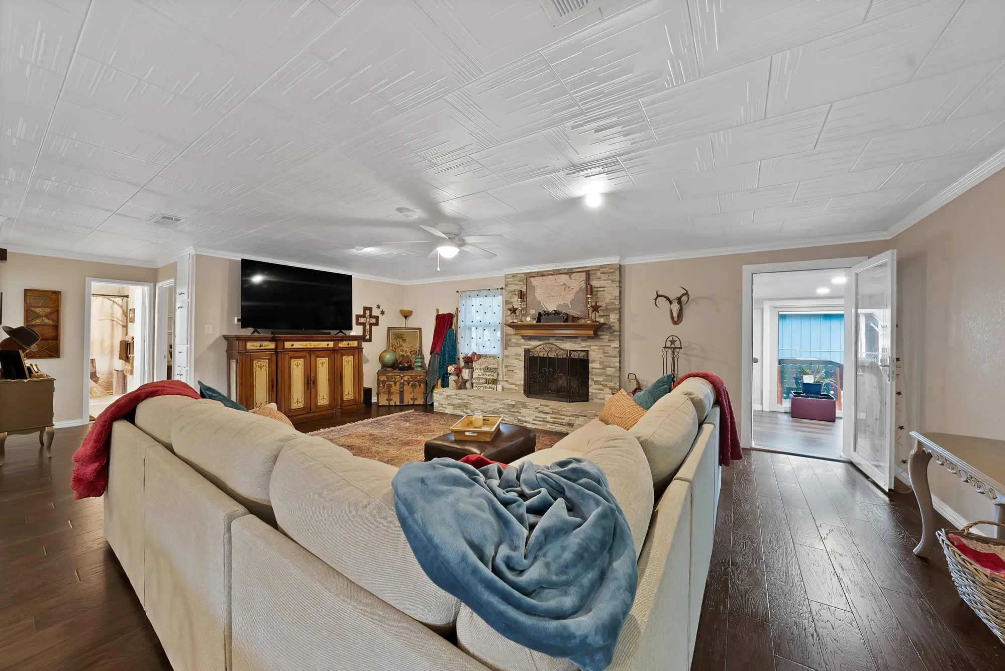 Living area featuring wood-finish flooring, a stone-faced fireplace, and a textured ceiling