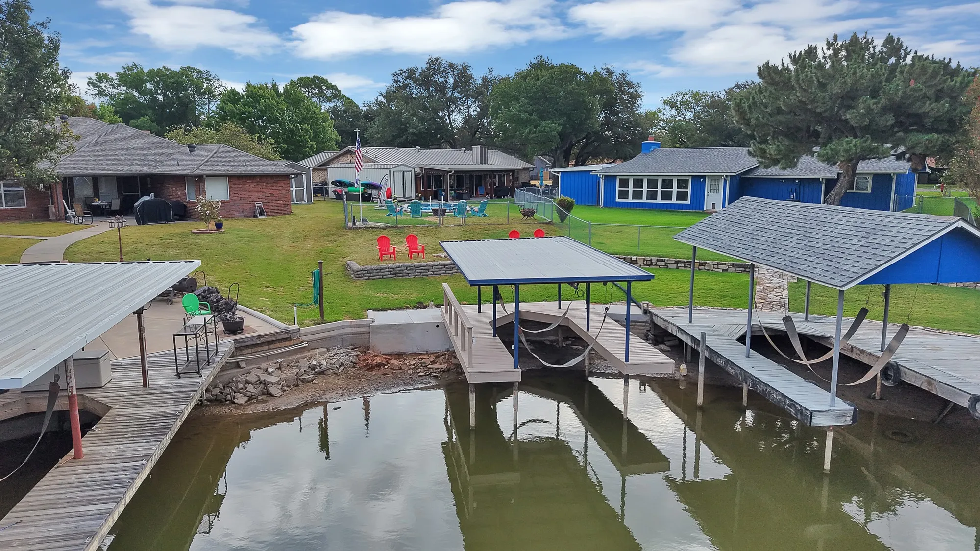 Waterfront property featuring  covered boat docks, a stone-clad retaining wall, and a large grassy area
