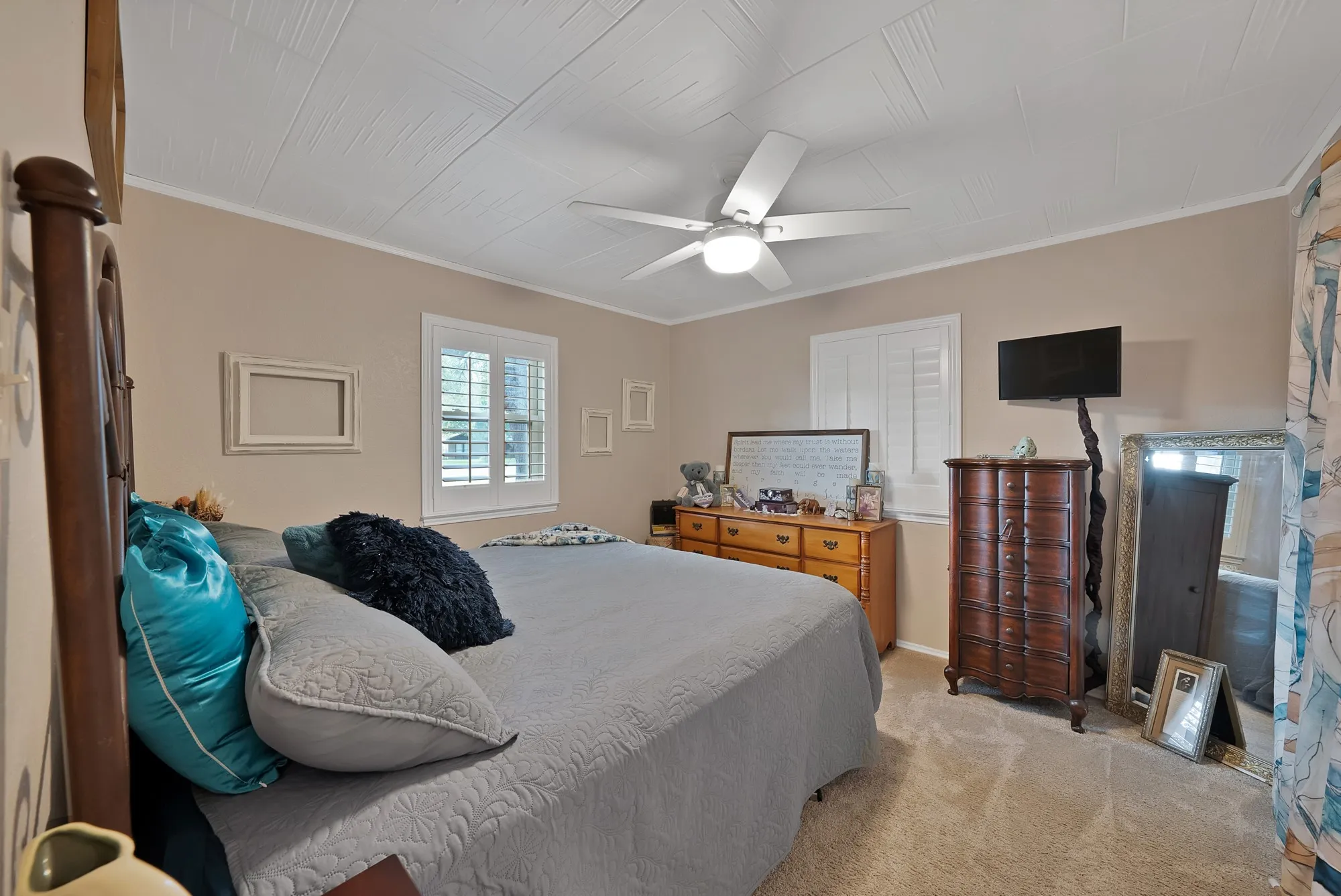 Textured ceiling, ceiling fan with integrated lighting, window with plantation shutters, light-toned wall paint, and carpeting