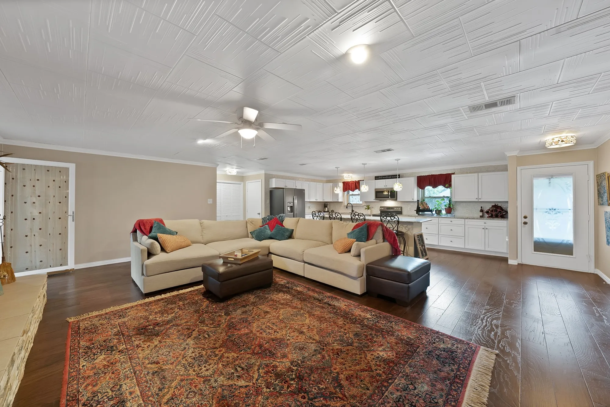 Expansive open-concept living space with dark wood-finish flooring, textured ceiling, and recessed lighting