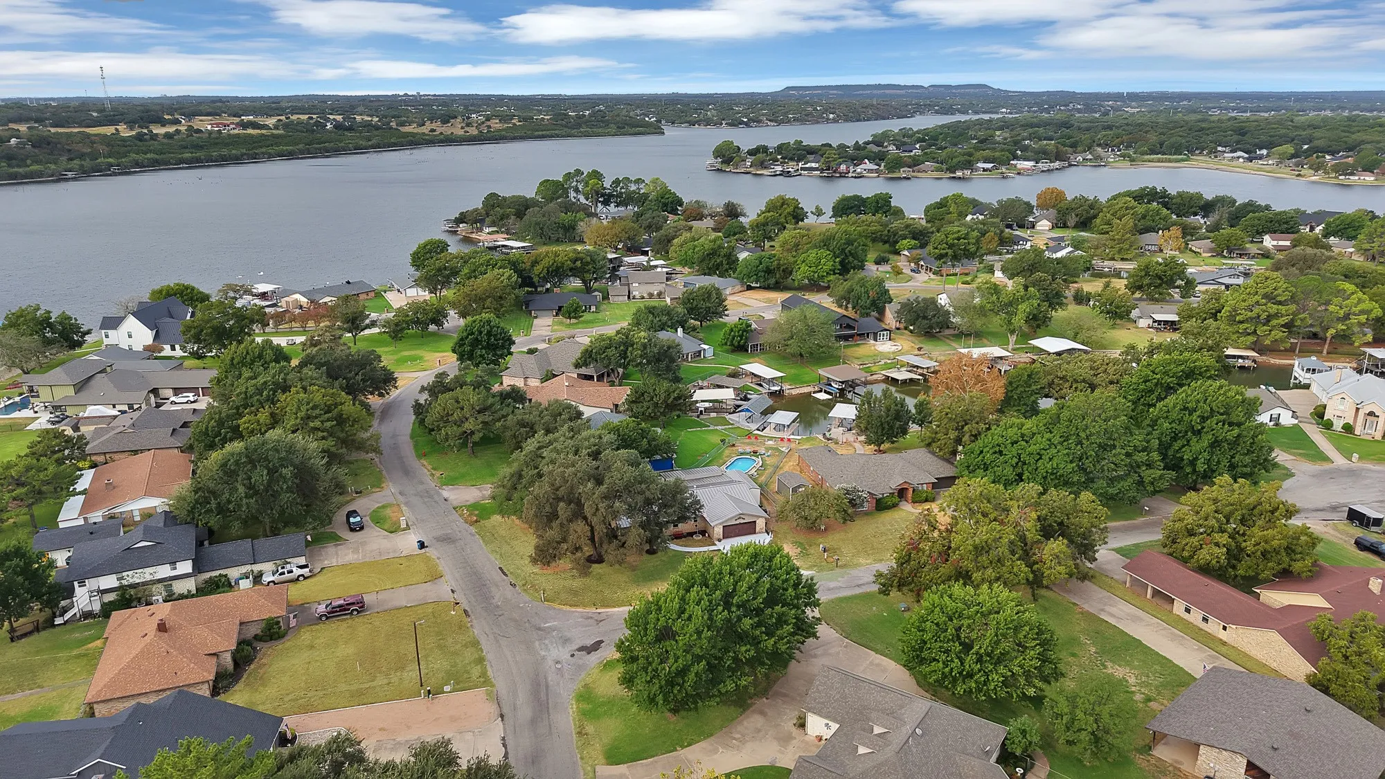 Residential community featuring mature trees, diverse home architecture, and waterfront properties