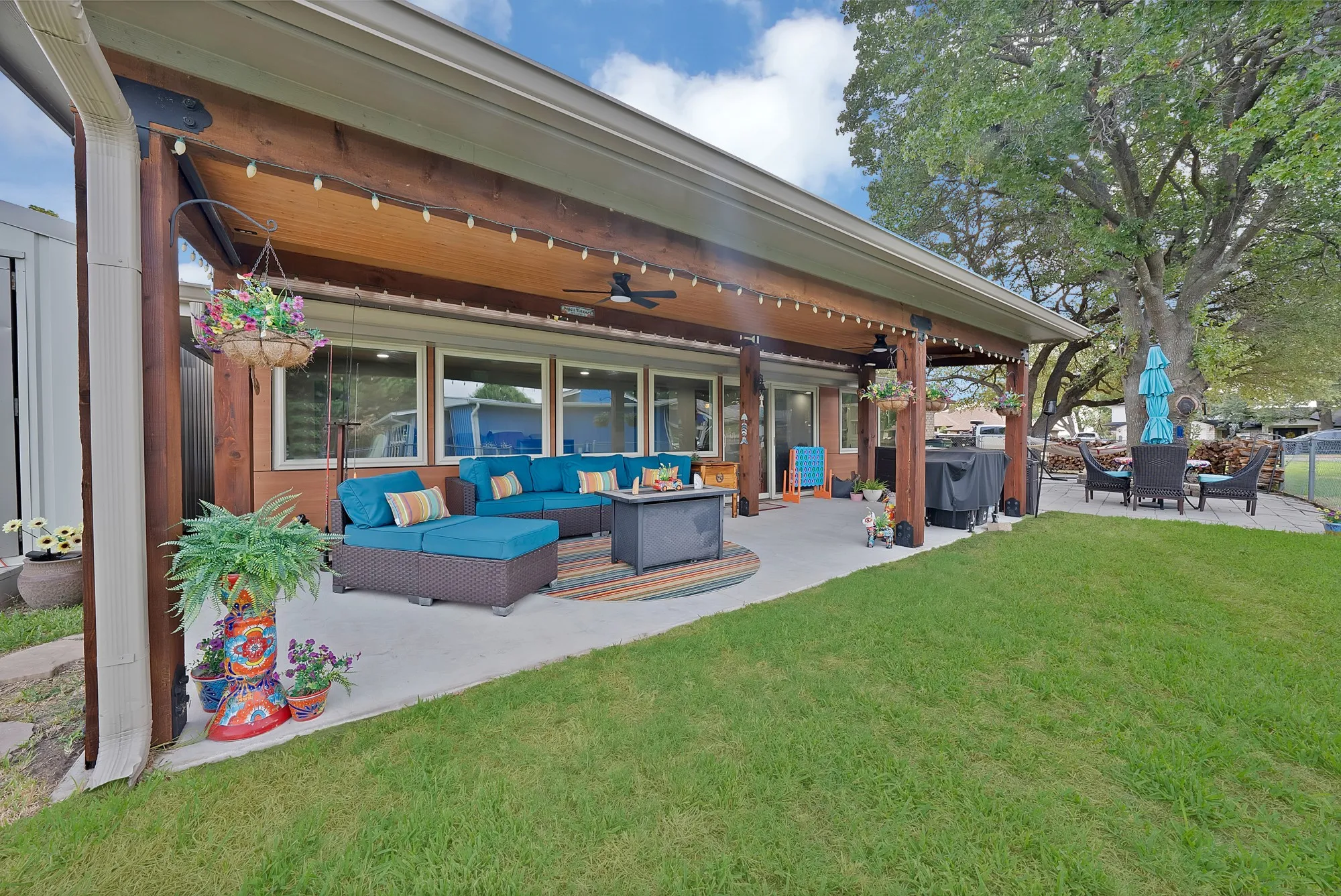 Expansive covered patio featuring a wood-beam ceiling, string lighting, and multiple windows