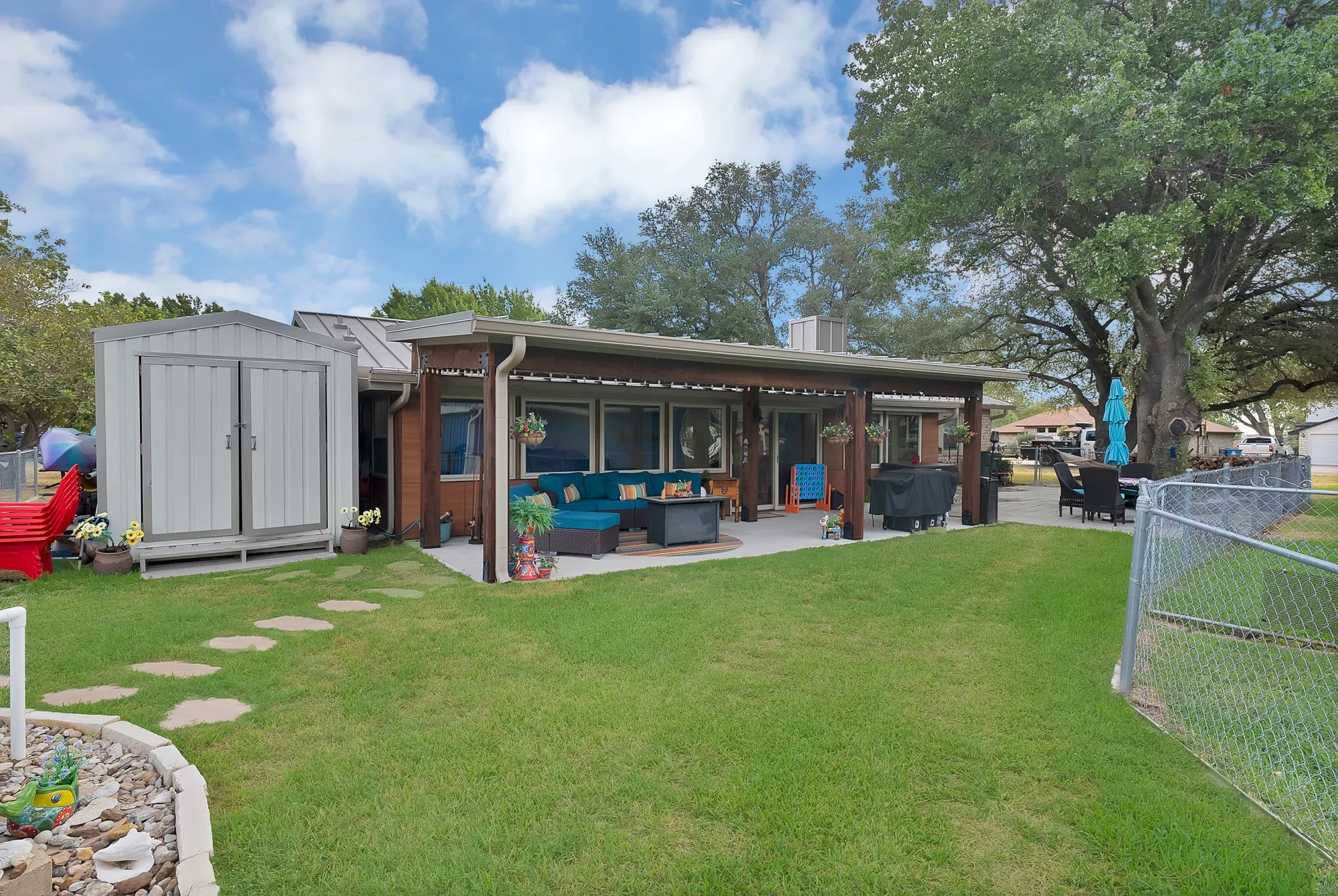 Expansive backyard with a covered patio, concrete surface, and a detached storage shed