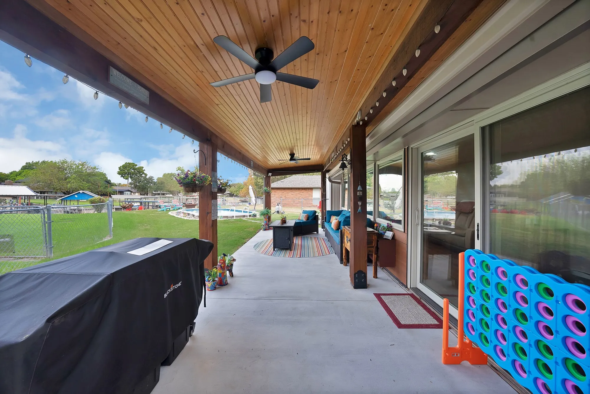 Expansive covered patio with a wood-finish ceiling, multiple ceiling fans, and concrete flooring