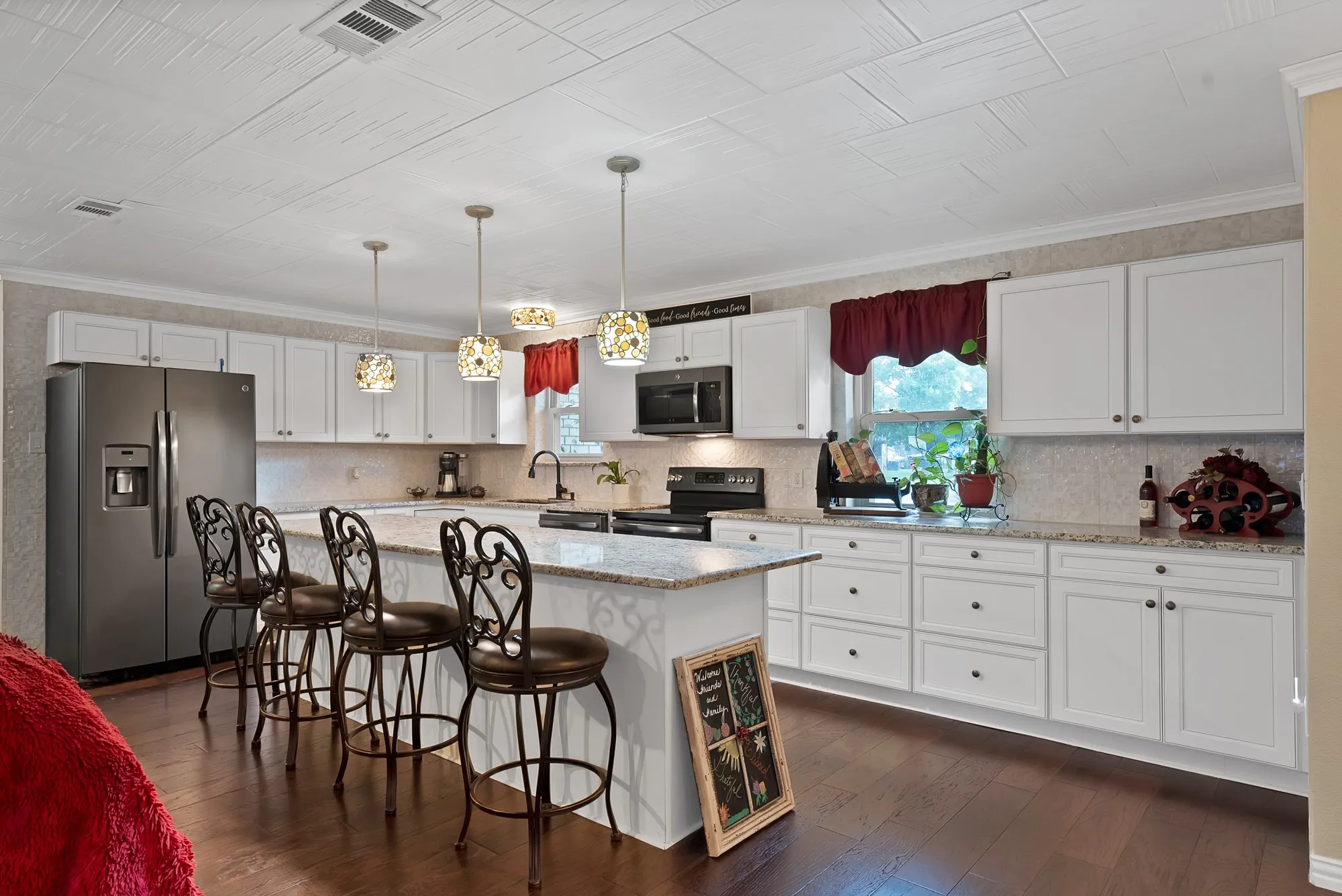 Spacious kitchen featuring white cabinetry, a large center island with seating, granite countertops, and dark wood-finish flooring