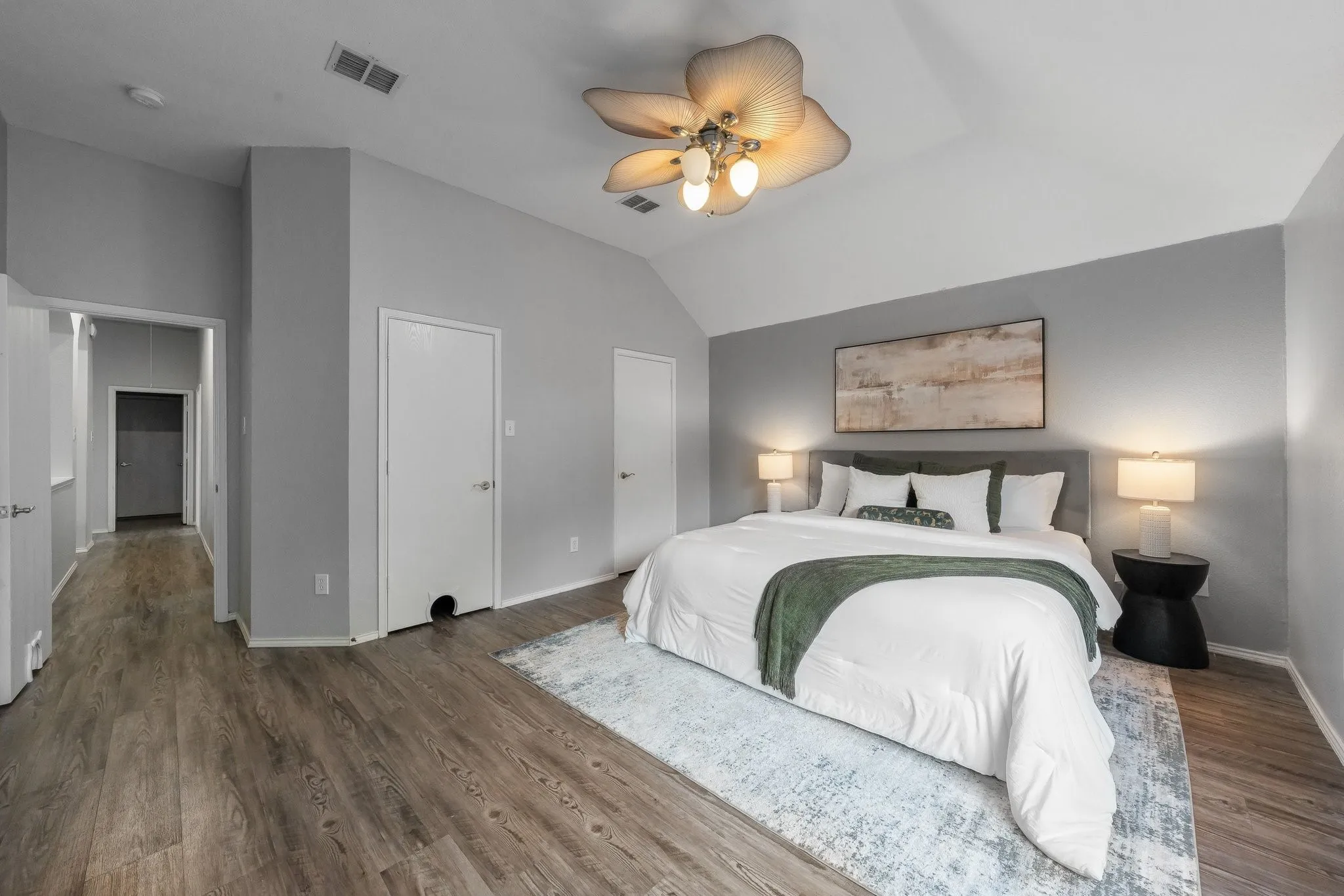 Vaulted ceiling, ceiling fan with integrated lighting, wood-finish flooring, two panel interior doors, and recessed lighting in the hallway