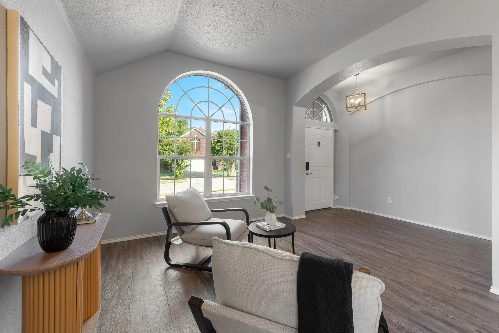 Vaulted ceiling with an arched window, wood-finish flooring, recessed entry, and an overhead light fixture
