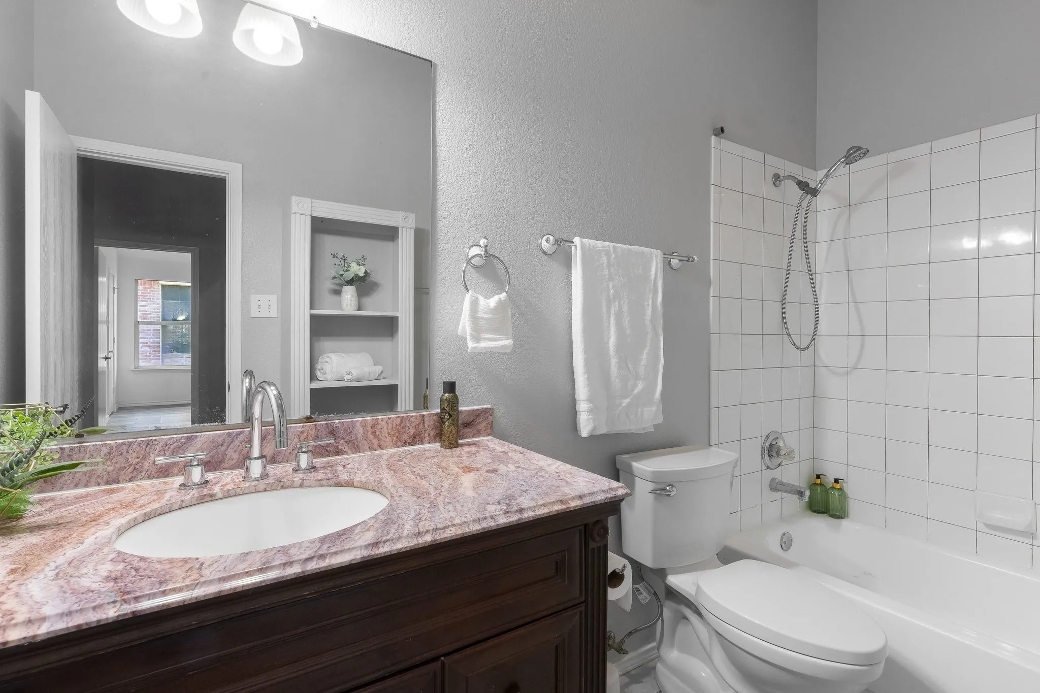 Vanity with an oval undermount sink, multi-tone countertop, and chrome faucet