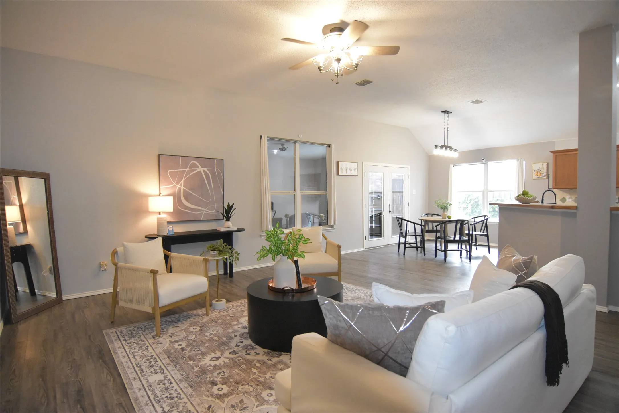 Vaulted ceiling with a ceiling fan, wood-finish flooring, and white interior walls