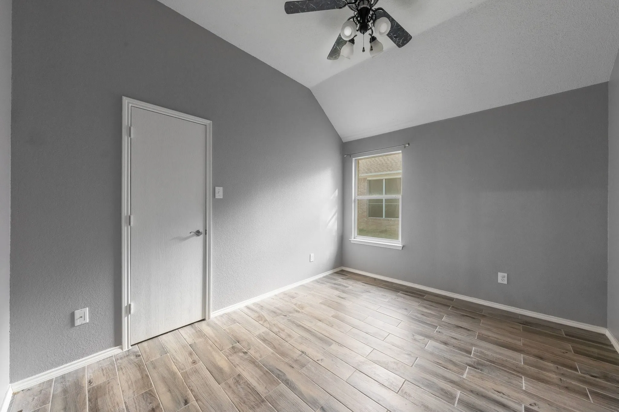 Wood-finish flooring, vaulted ceiling, and a ceiling fan with integrated lighting