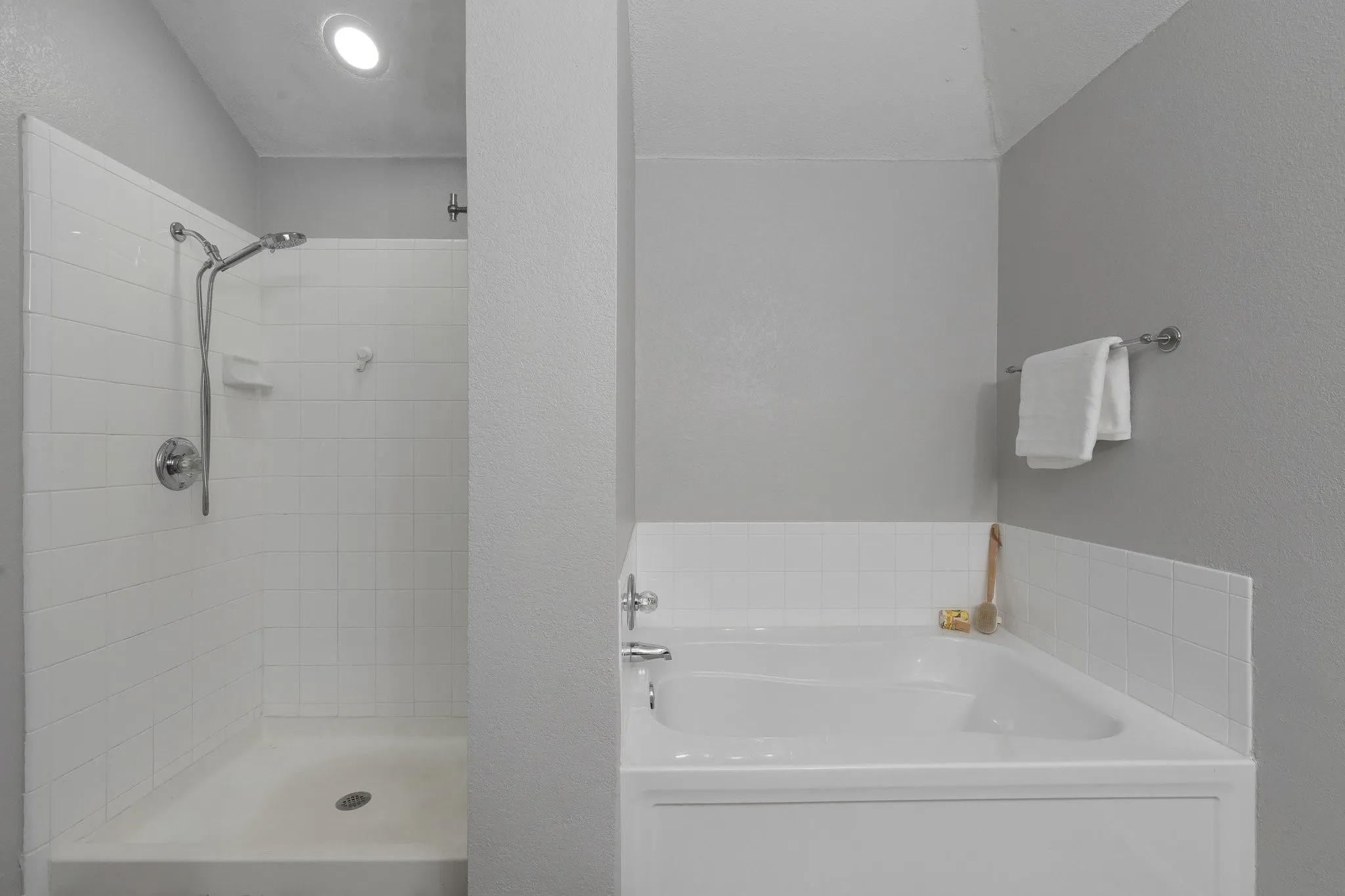 Recessed ceiling lighting, white subway tile shower surround, chrome shower fixtures, built-in bathtub, and chrome towel bar