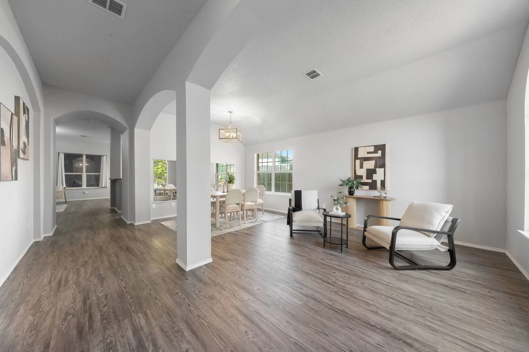Wood-finish flooring throughout, multiple arched doorways, vaulted ceiling, and recessed lighting