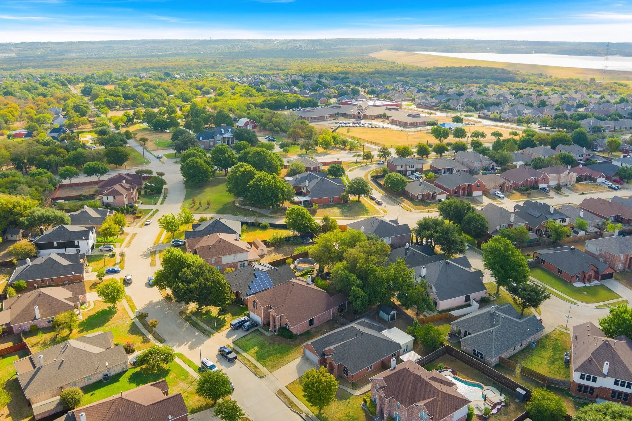 Aerial perspective of a residential neighborhood featuring detached homes with varied rooflines and a mix of brick and siding exteriors