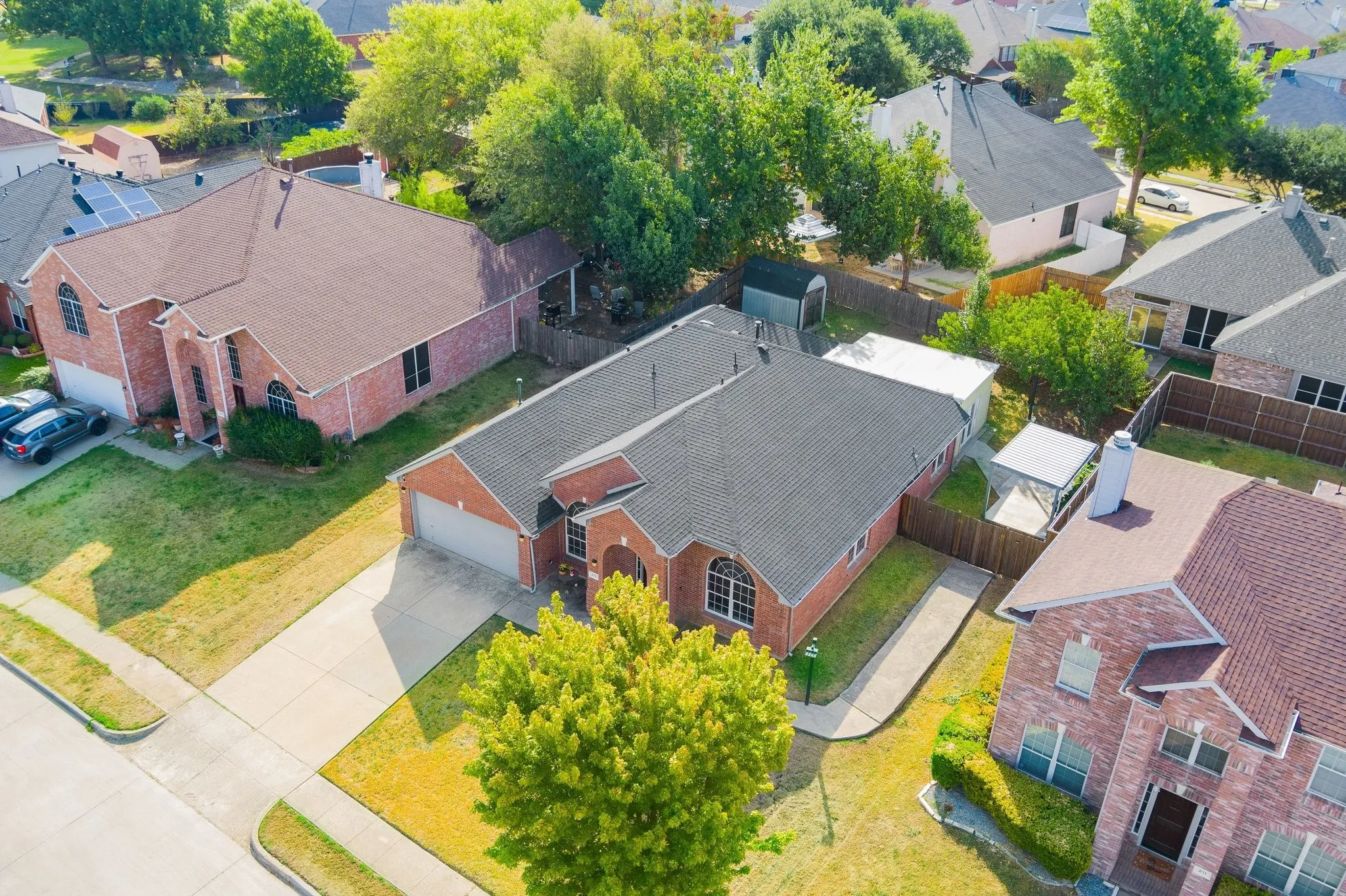 Brick exterior residence with a dark shingled roof, attached garage, and a concrete driveway