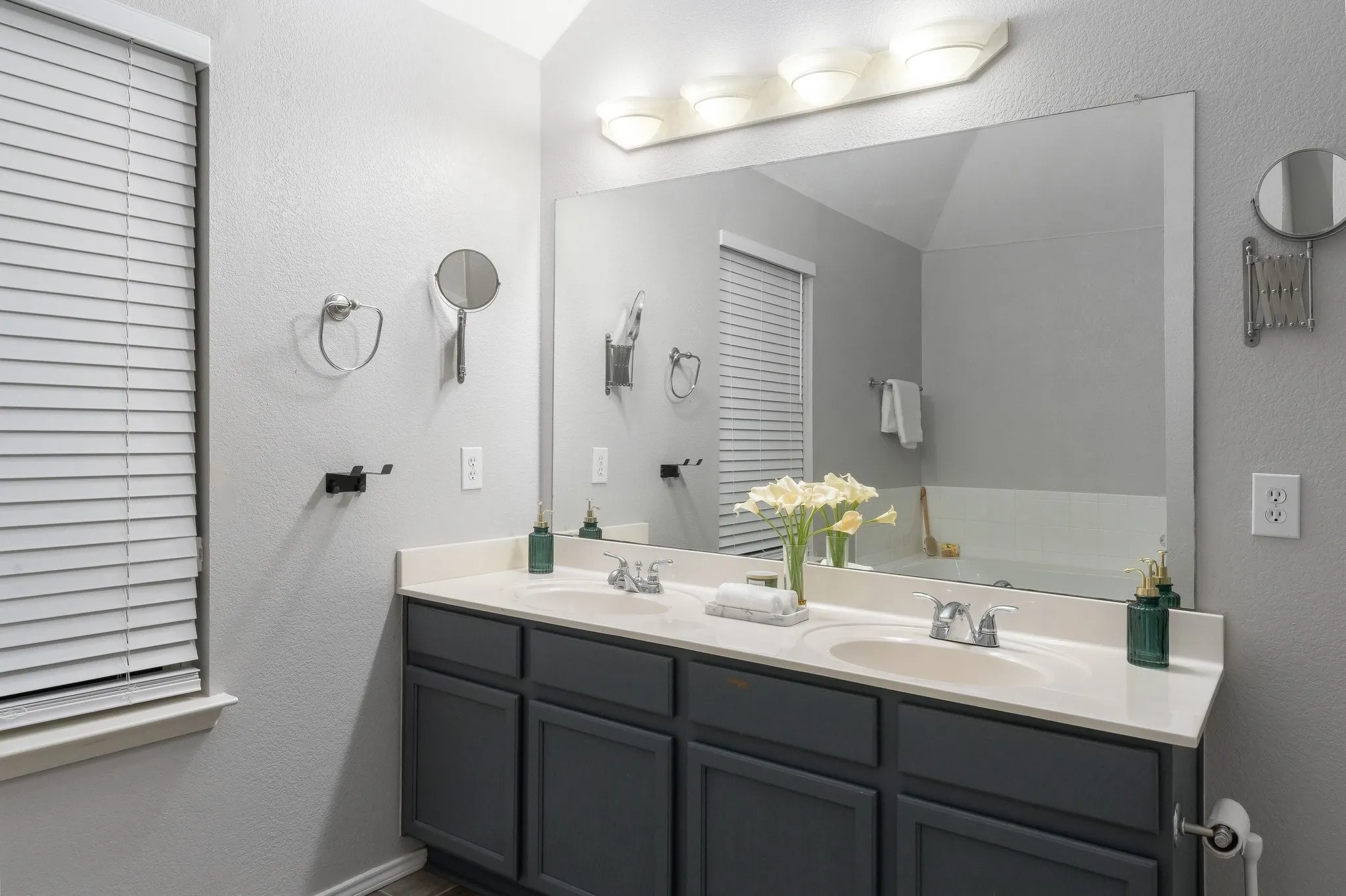 Double vanity with integrated sinks, light-toned countertop, dark-toned cabinetry, and a full-width mirror