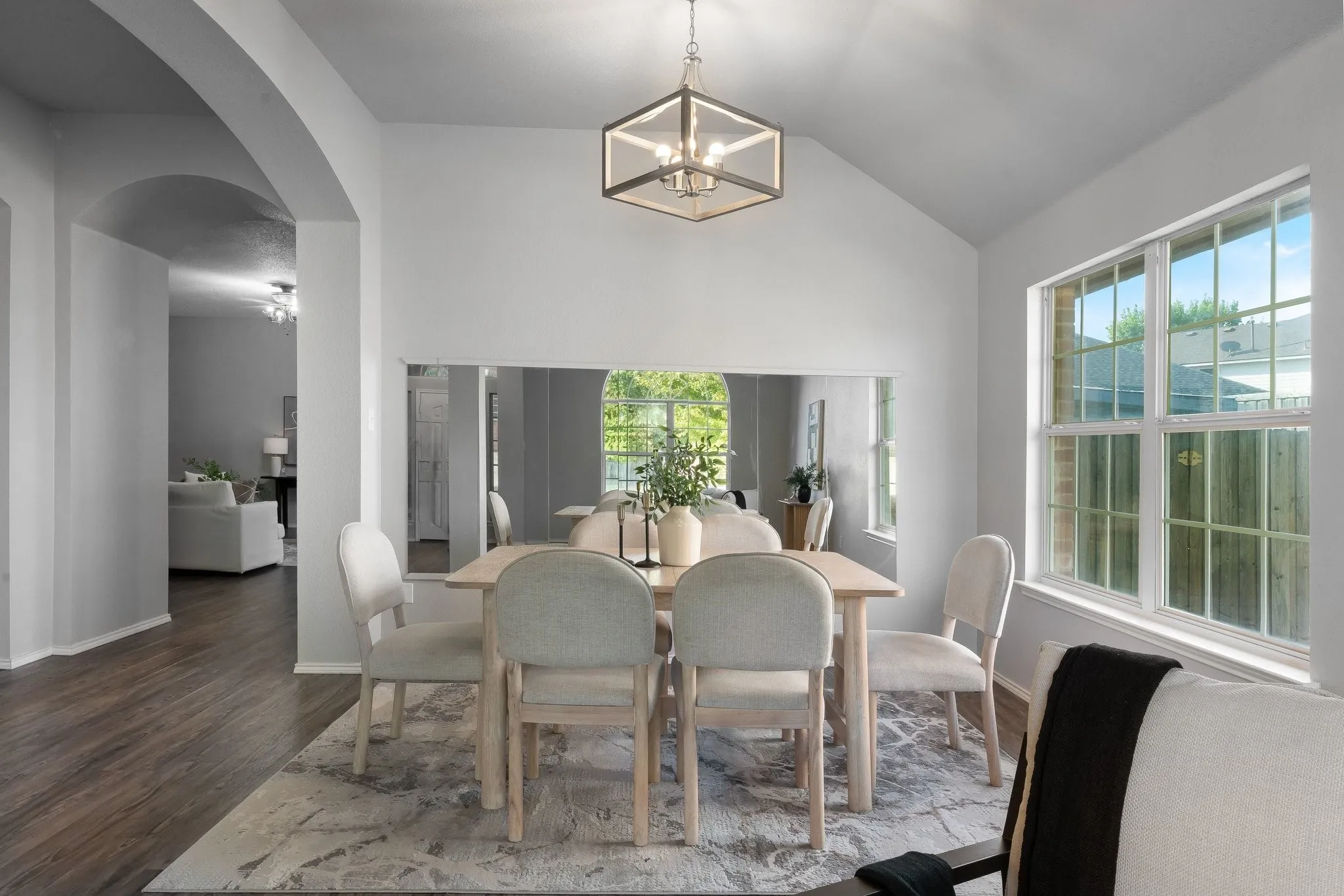 Vaulted ceiling dining area featuring wood-finish flooring, an arched doorway, and an open geometric pendant light fixture
