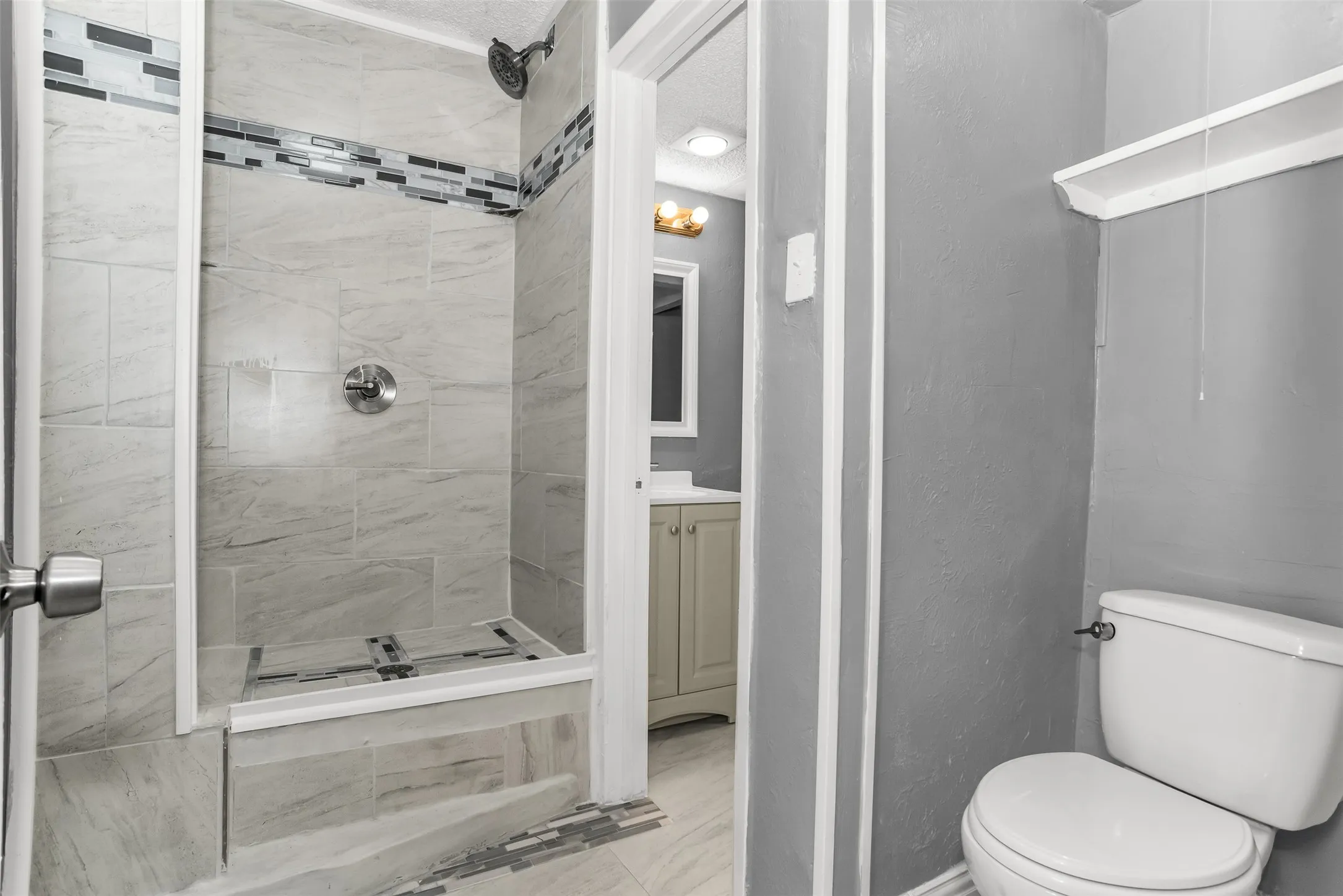 Walk-in shower with tiled walls and decorative accent band