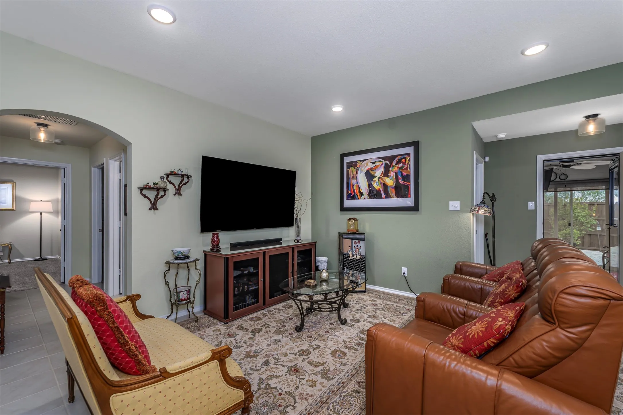 Recessed ceiling lighting, arched doorway, wood-finish media console, and light-toned wall paint