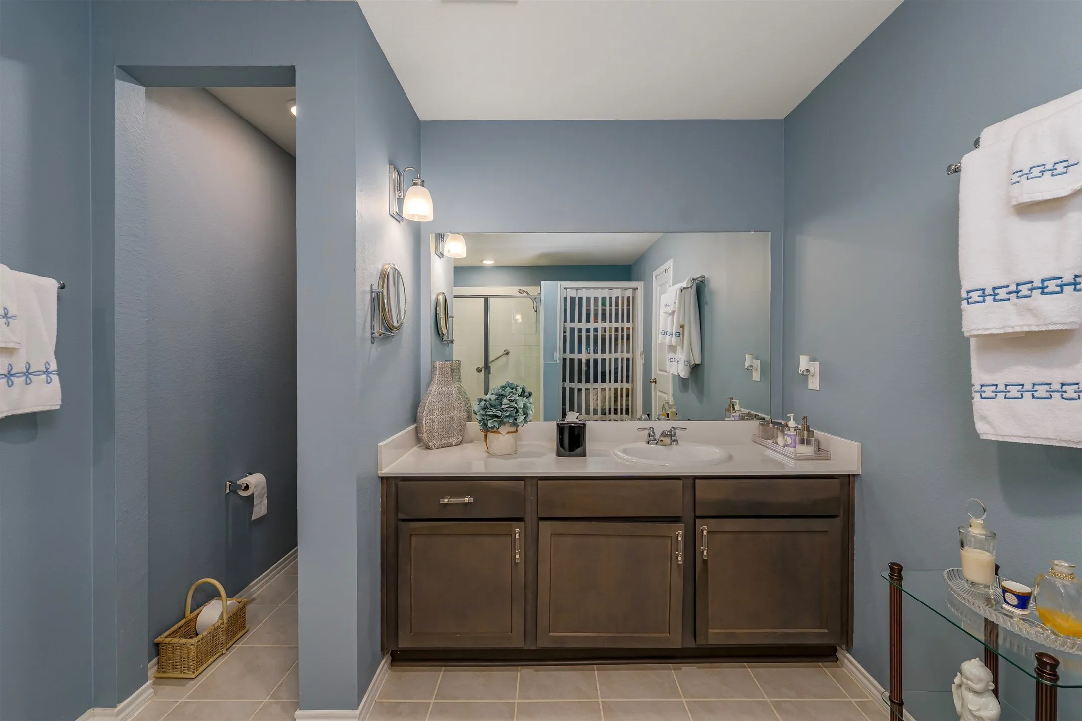 Double vanity with integrated sinks, framed mirror, and warm-toned wall sconces