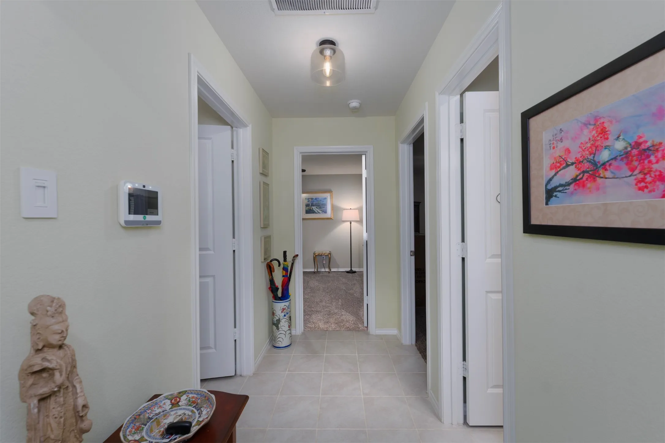 Hallway with light-toned walls, tile flooring, and multiple doorways