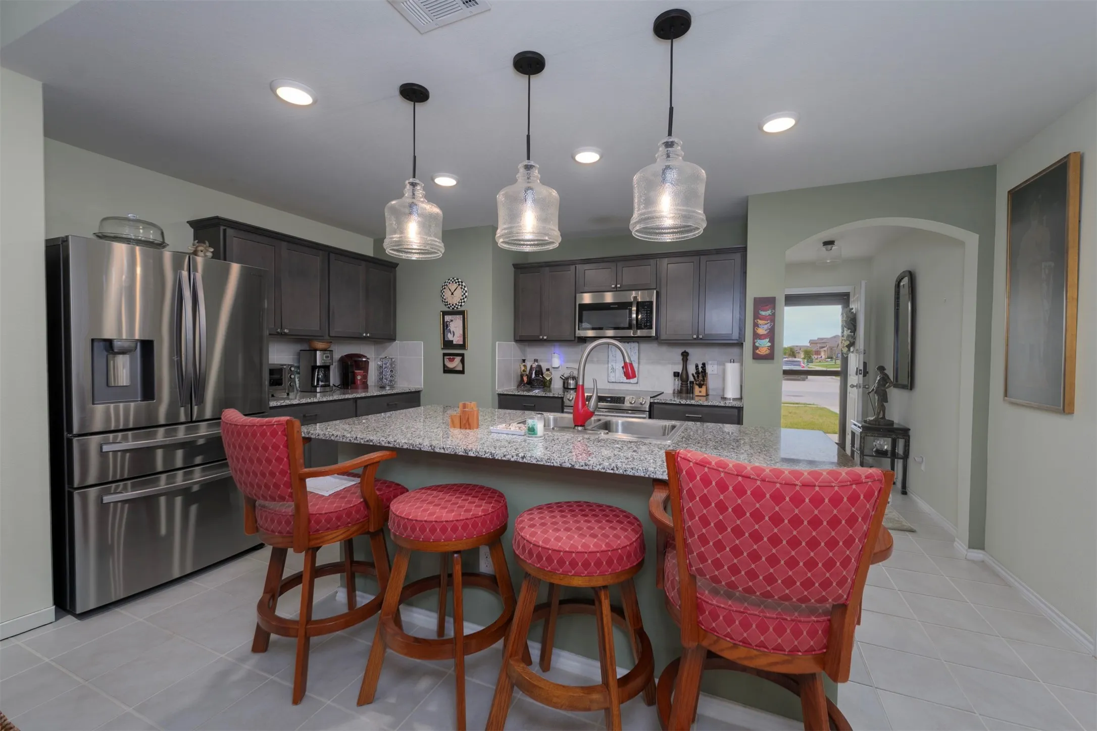 Well-appointed kitchen featuring stainless steel appliances, dark wood cabinetry, a large center island with counter seating, and recessed lighting