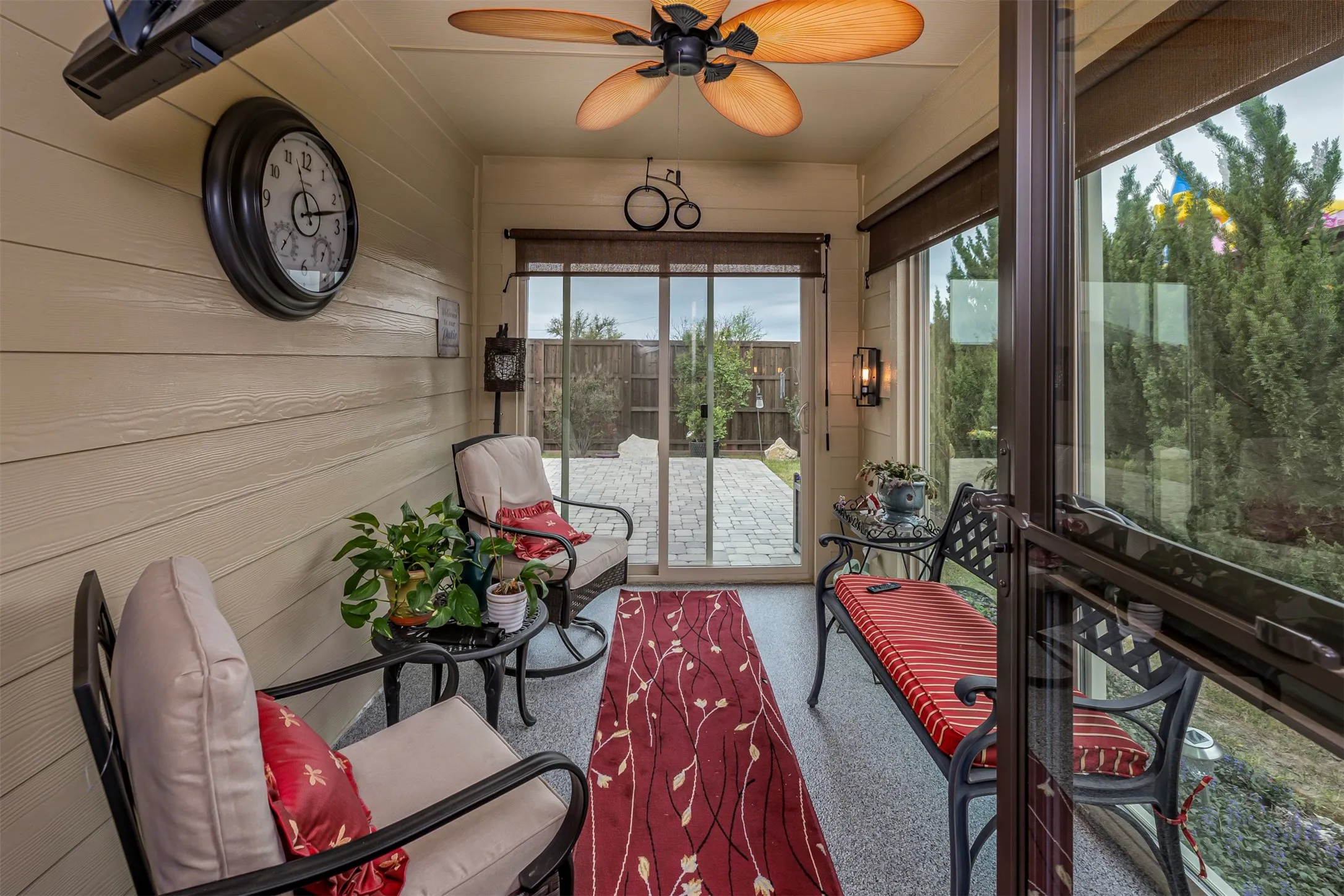 Enclosed patio with wood-finish walls, a ceiling fan, and sliding glass doors