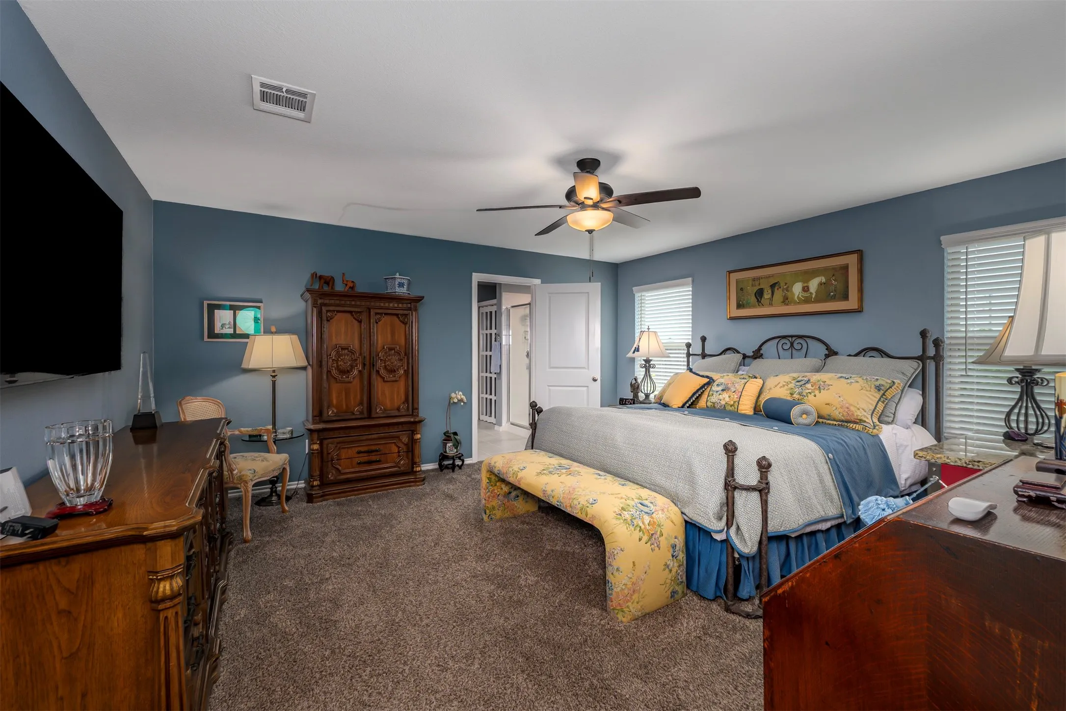 Carpet flooring, ceiling fan with integrated lighting, multiple windows with blinds, and blue painted walls