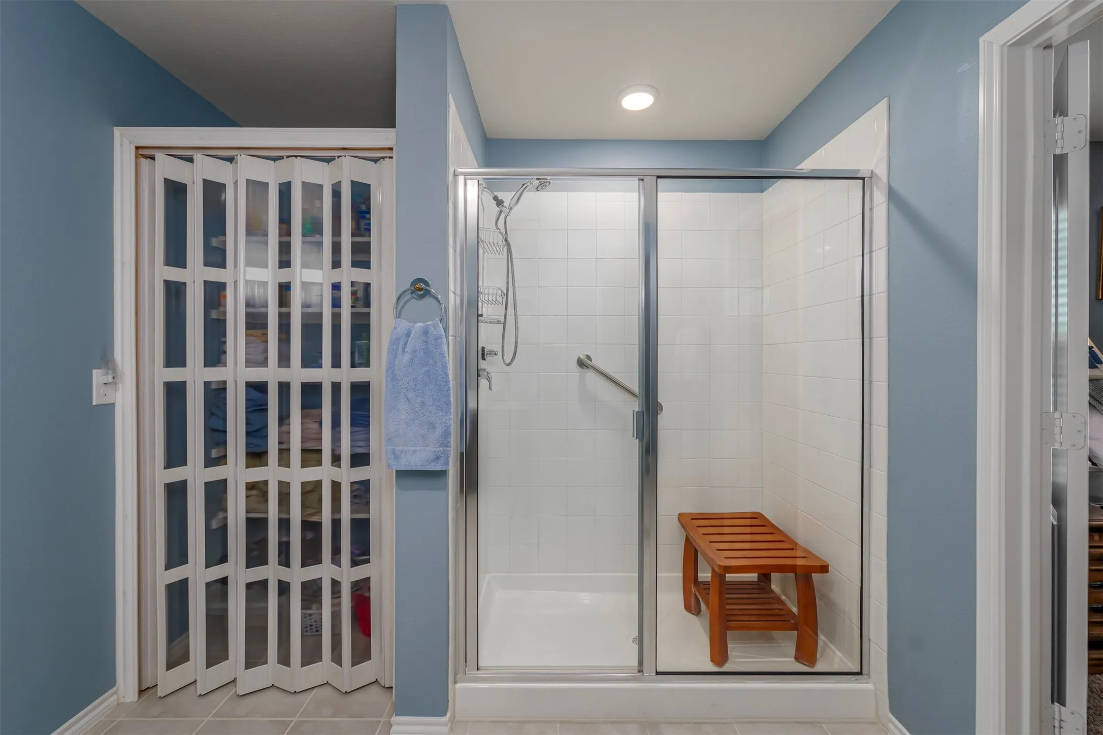Glass-enclosed shower with white subway tile, a chrome showerhead, and a grab bar