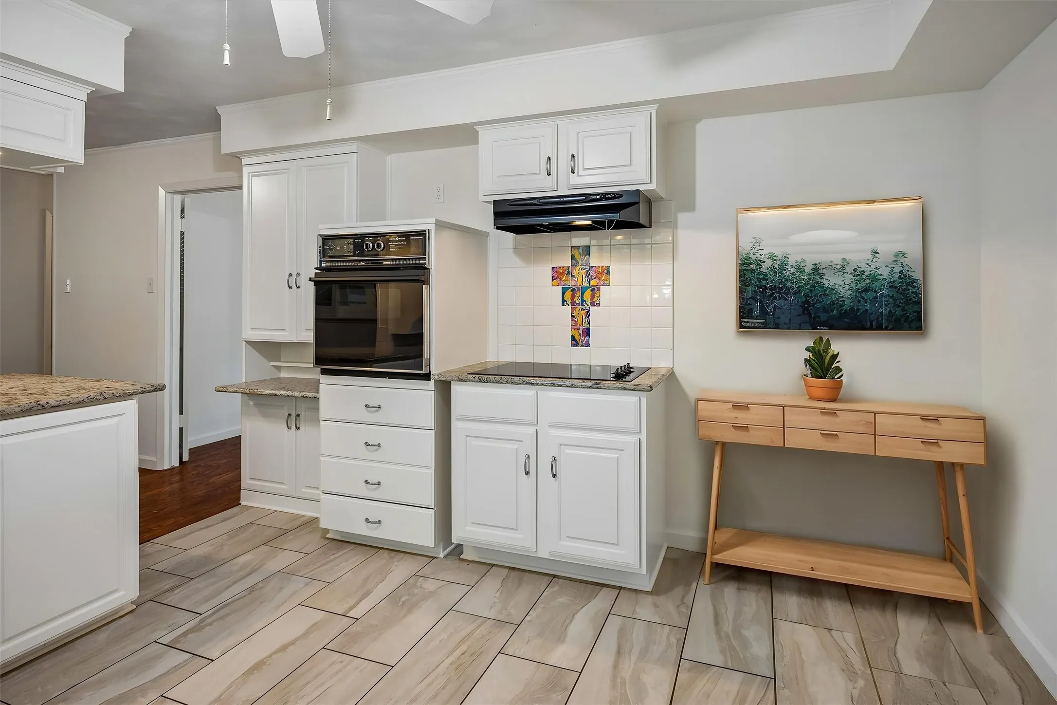 VIRTUALLY STAGED Cooktop with range hood, a little desk area if needed and a colorful backsplash
