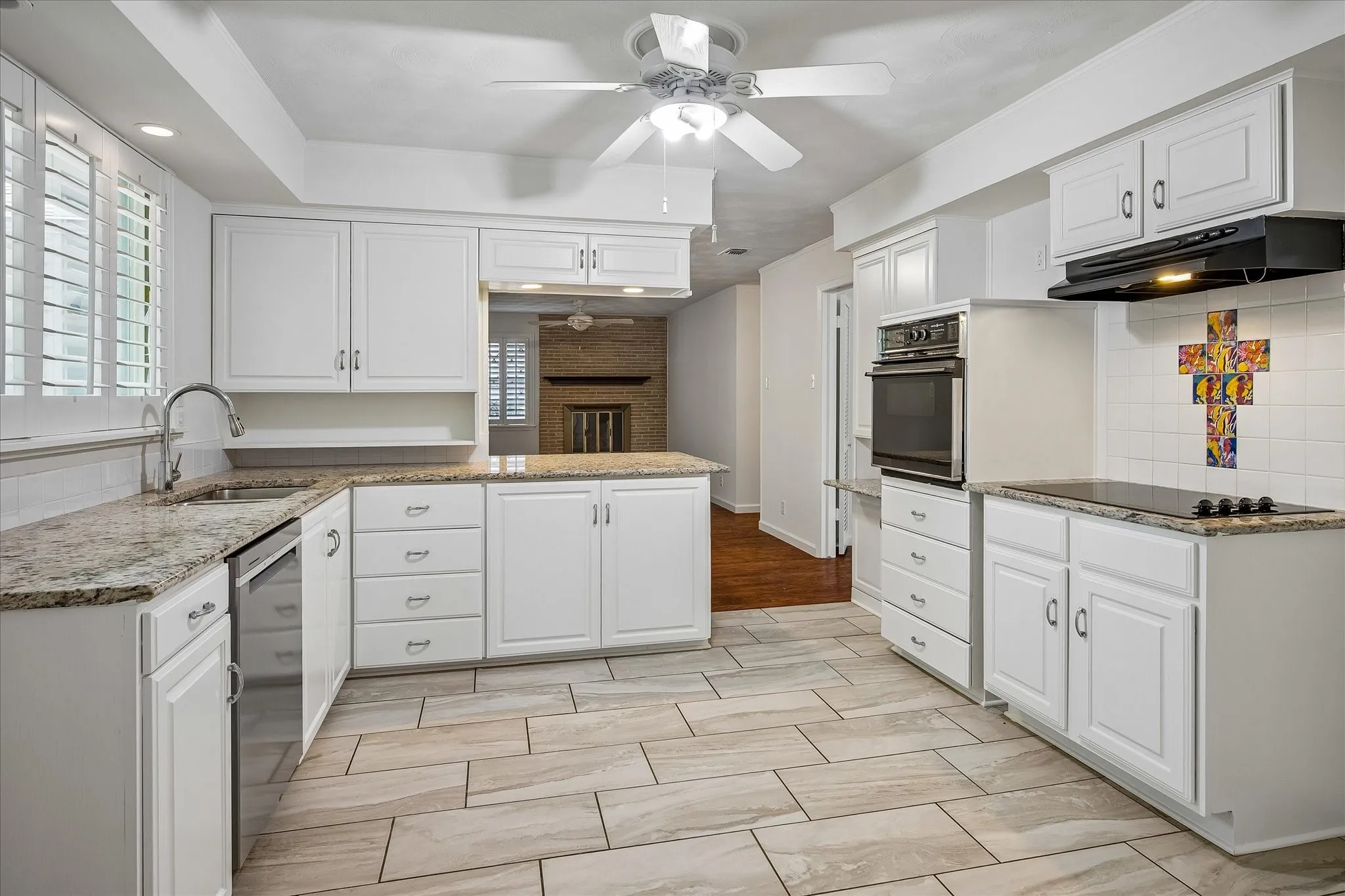 Kitchen featuring white cabinetry, granite countertops, tile flooring, a built-in oven, and a cooktop