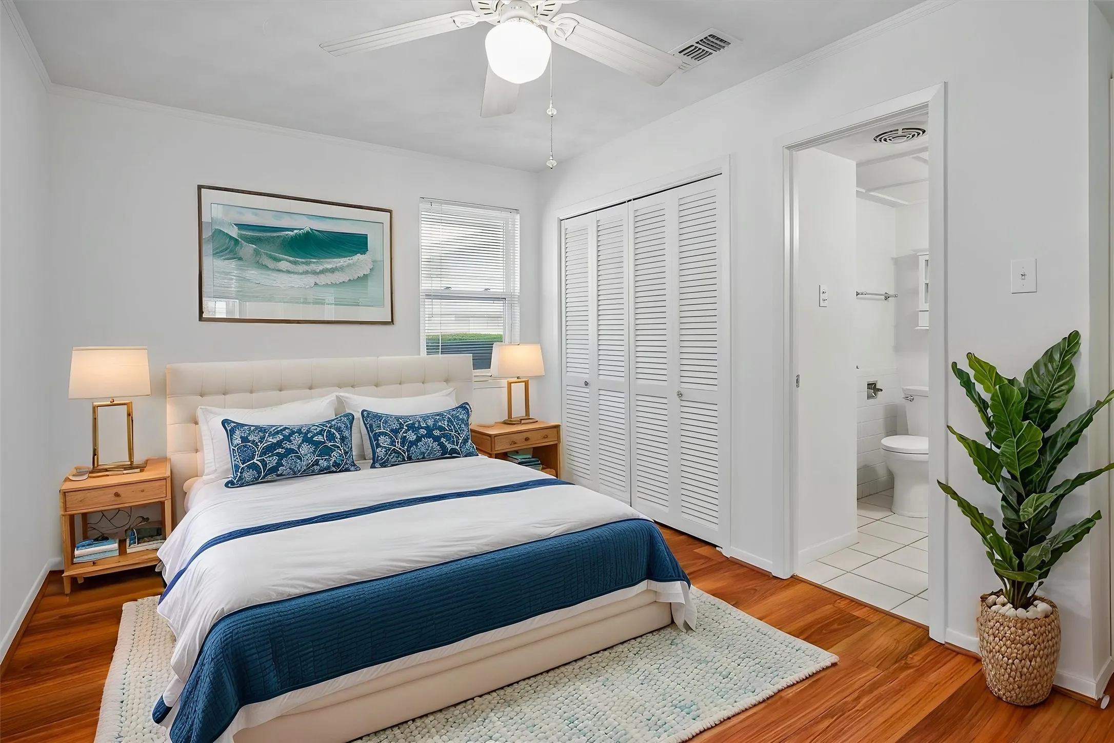 VIRTUALLY STAGED The primary bedroom is split from the others and boasts white walls, louvered closet doors, and ceiling fan with integrated lighting