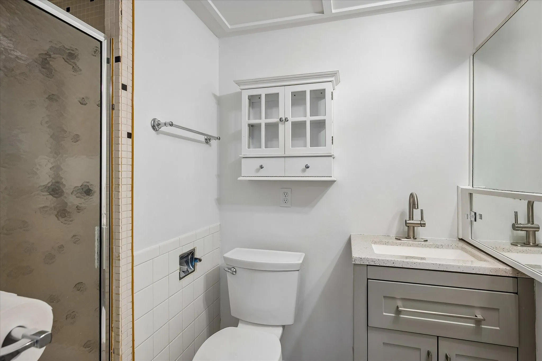 Attached to the bedroom, this updated vanity with a light-toned countertop, a retro wall-mounted medicine cabinet and a shower with a textured glass enclosure