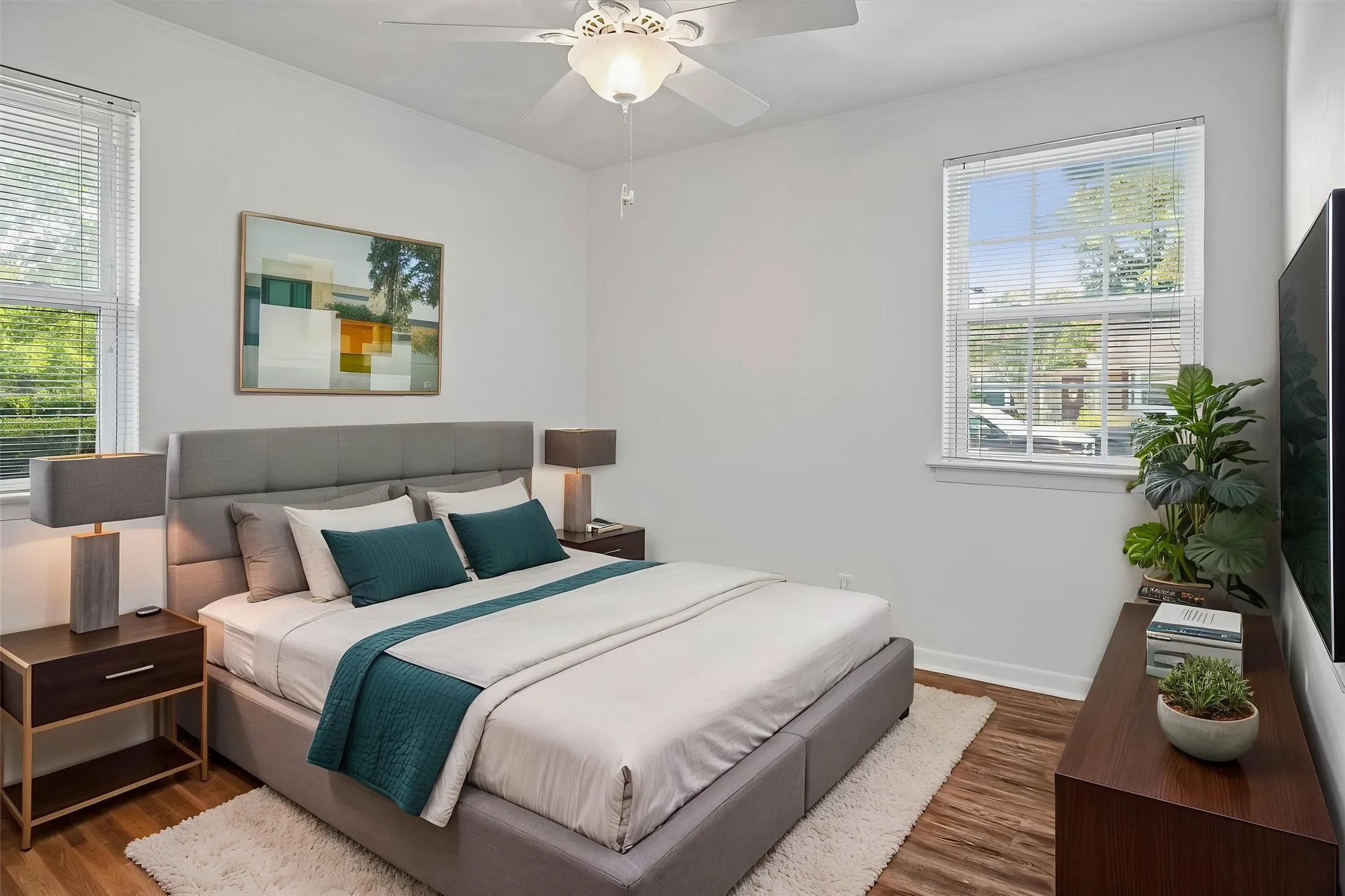 VIRTUALLY STAGED Two large windows with blinds, and a ceiling fan with light fixture
