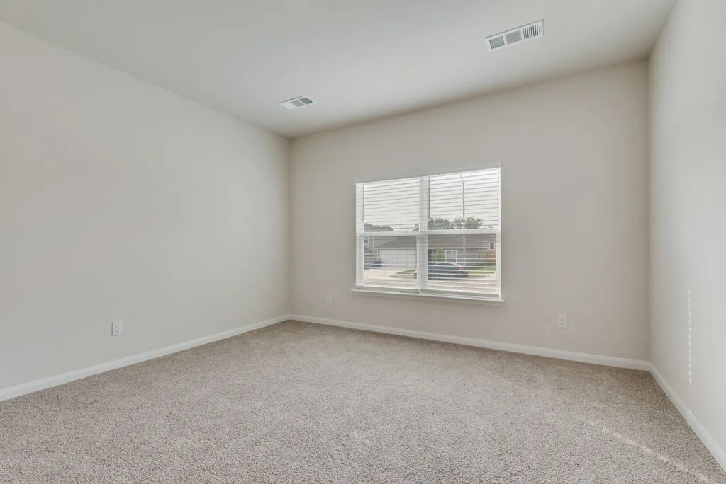Sloped ceiling with recessed lighting, neutral tone carpeting, and a window with blinds