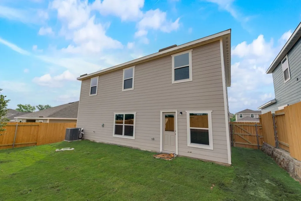 Two-story exterior with siding, multiple windows, and a rear access door> Grass virtually Staged