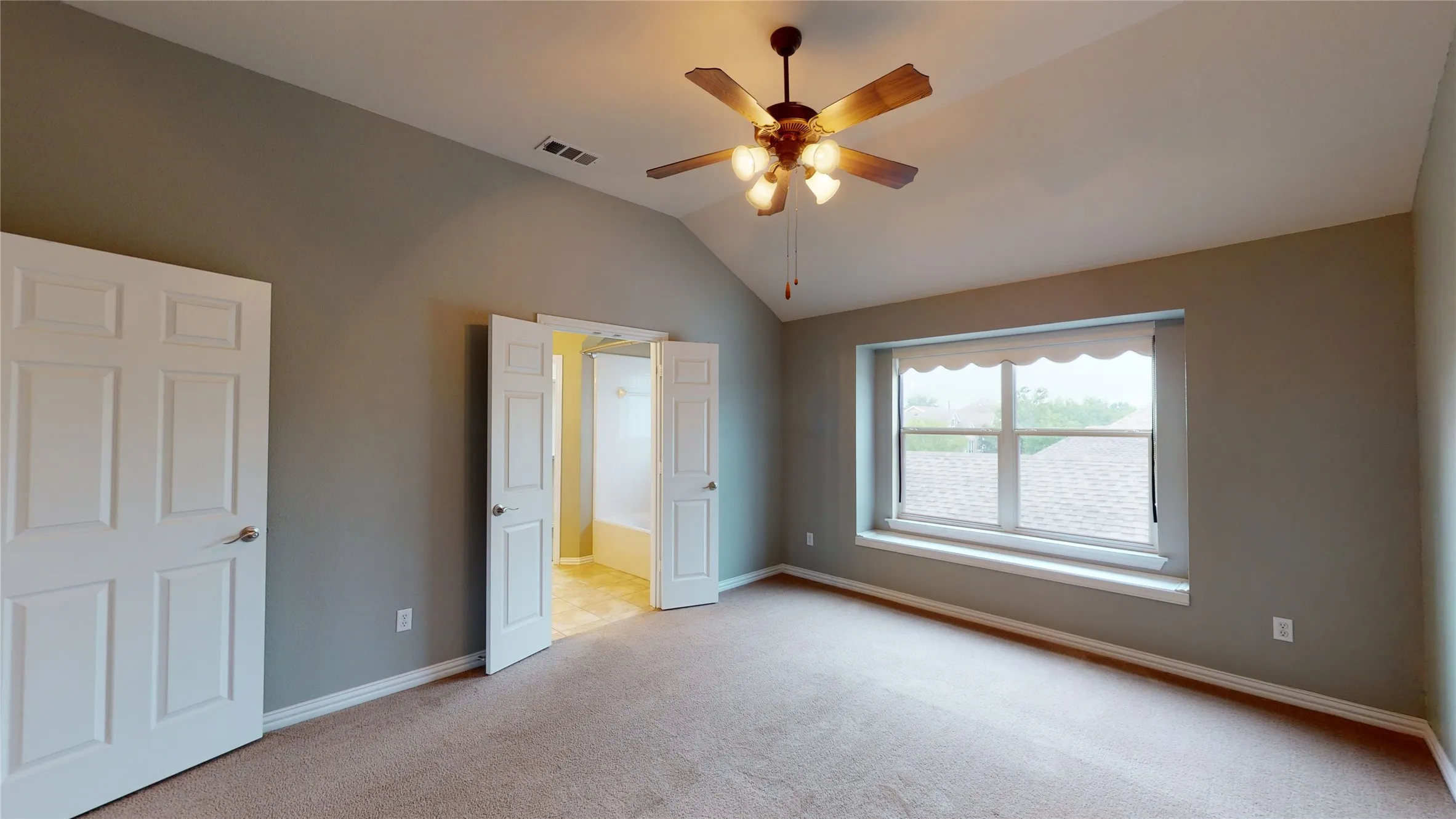 Primary bedroom is spacious with high ceilings.