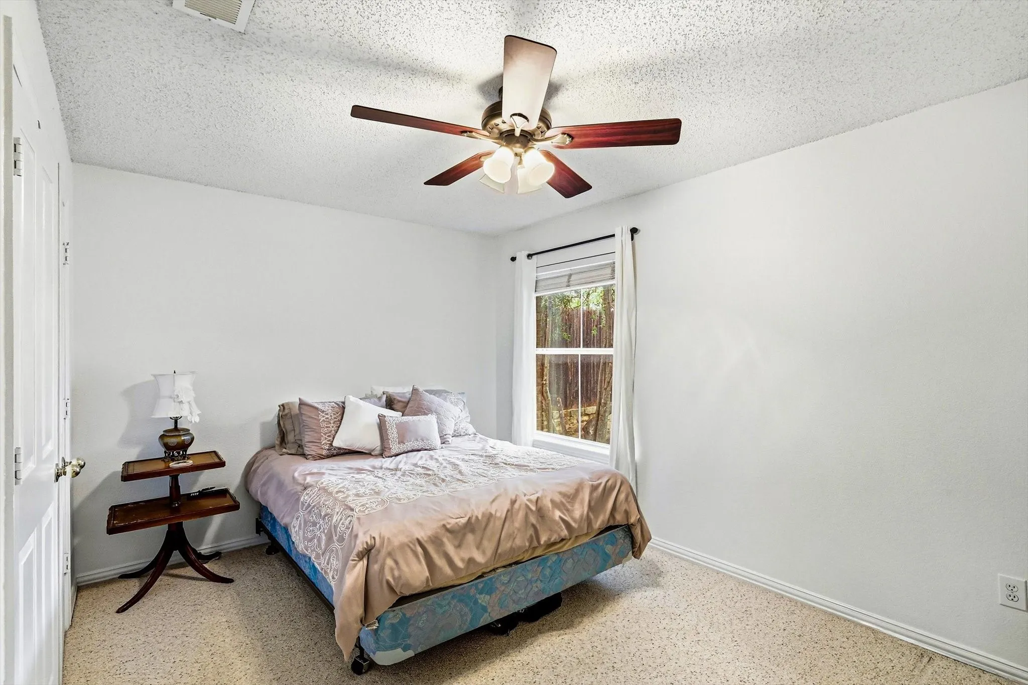 White interior walls, ceiling-mounted light fixture with fan, window with white trim, and light-colored carpet