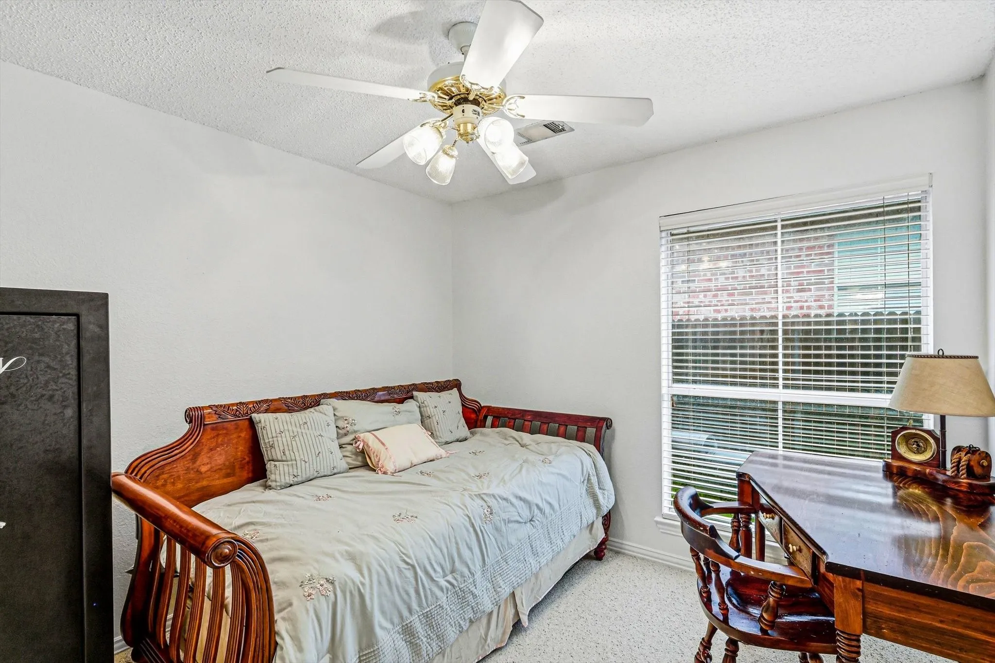 White walls complemented by textured carpeting, a window with horizontal blinds, and a ceiling fan with integrated lighting
