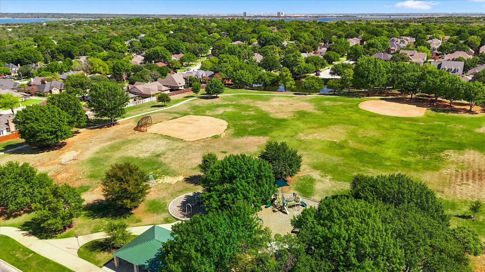 Expansive green space featuring two baseball fields, a playground area, and a covered pavilion