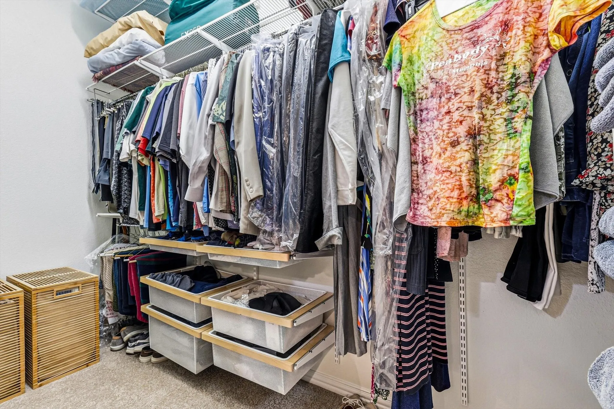 Integrated closet system featuring wire shelving, multiple hanging rods, and pull-out storage bins