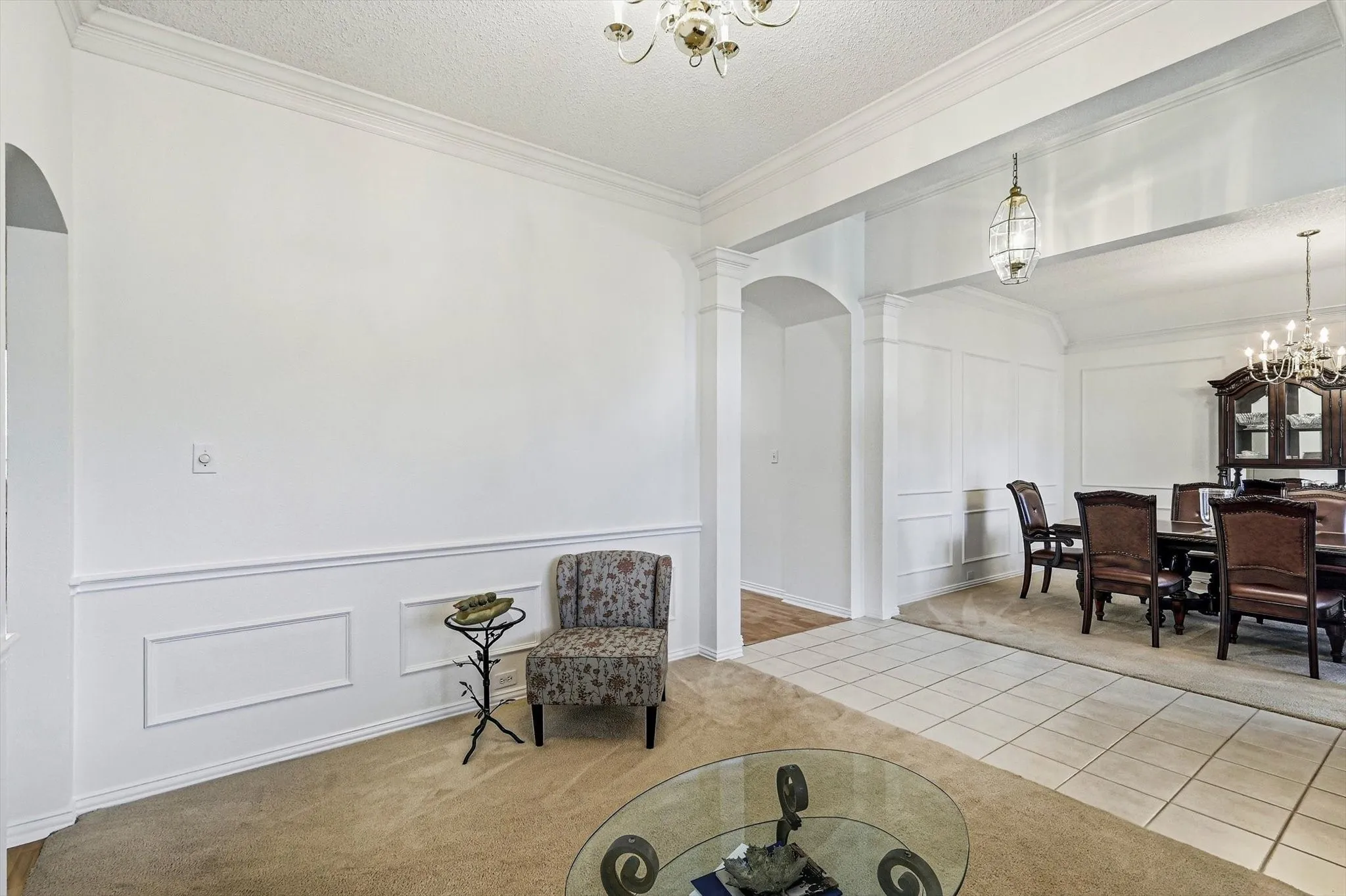 Formal dining area with chandelier and wainscoting, featuring tile flooring and an arched entryway