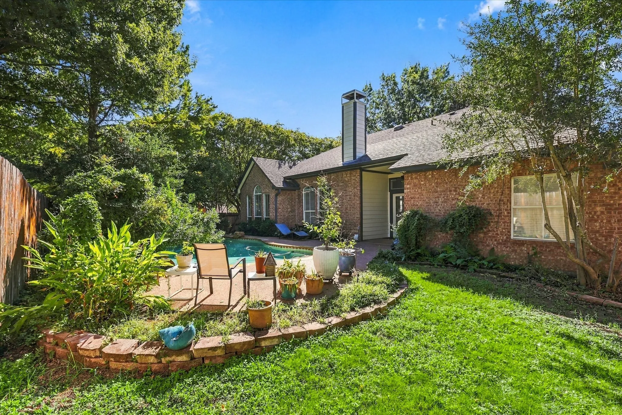 Brick exterior with a gabled roof, a prominent chimney, and a fenced yard