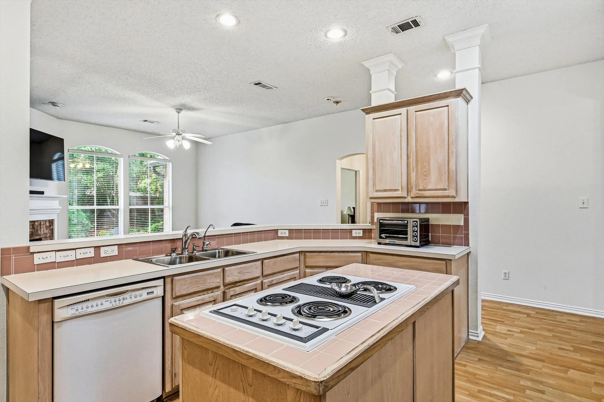 Kitchen featuring wood-finish cabinetry, tile countertops, a built-in electric cooktop, and a double basin sink
