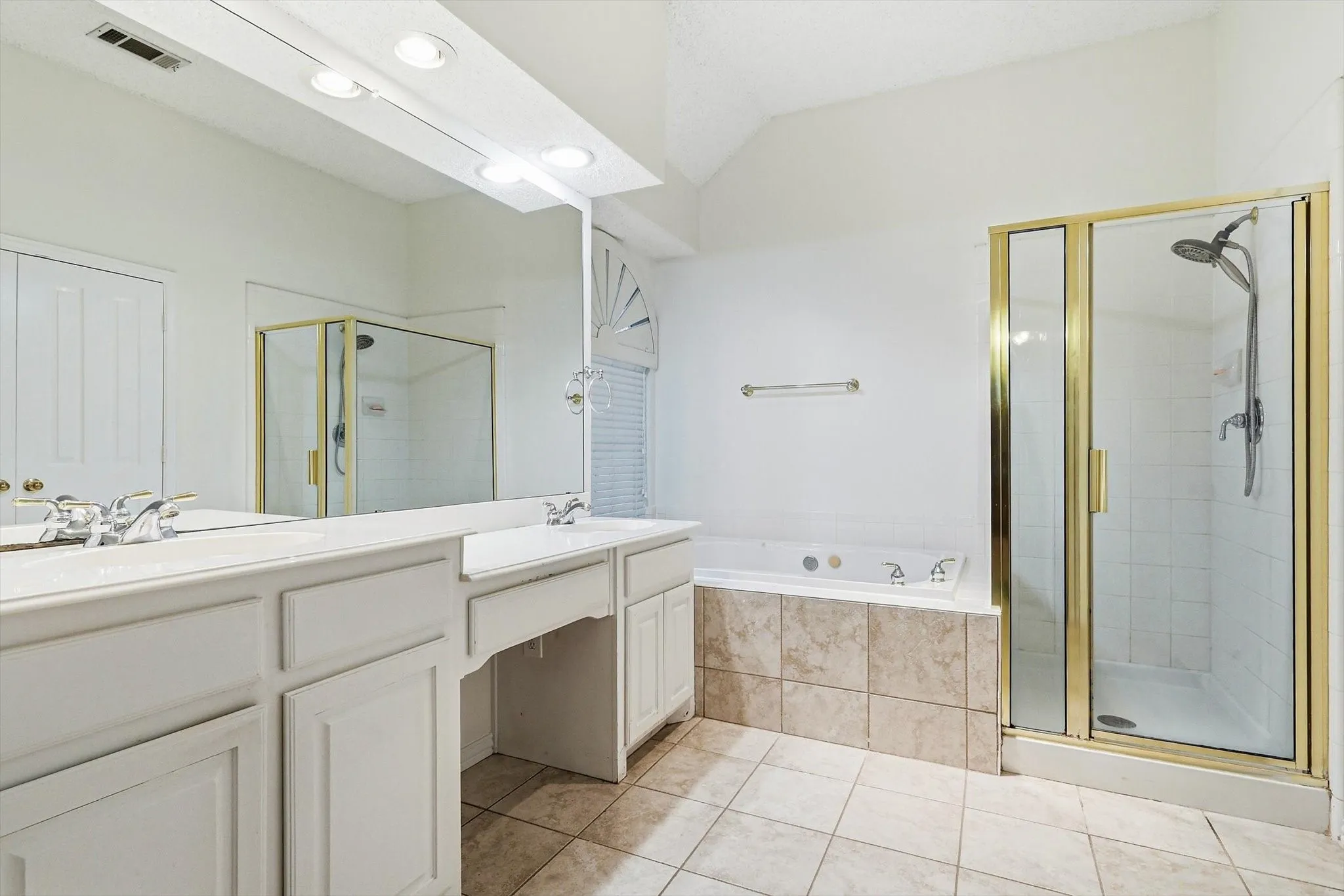Dual vanity with white cabinetry, tile flooring, built-in bathtub with tiled surround, and a glass-enclosed shower