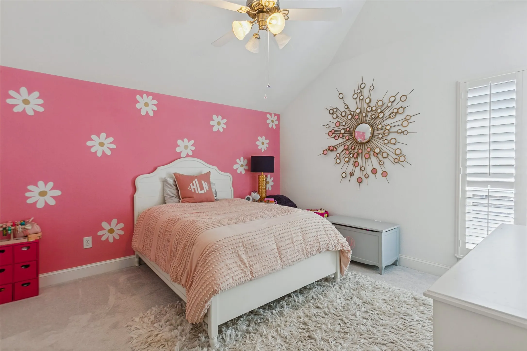 Secondary bedroom with Vaulted ceiling, white plantation shutters, ceiling fan with integrated lighting, and pink accent wall