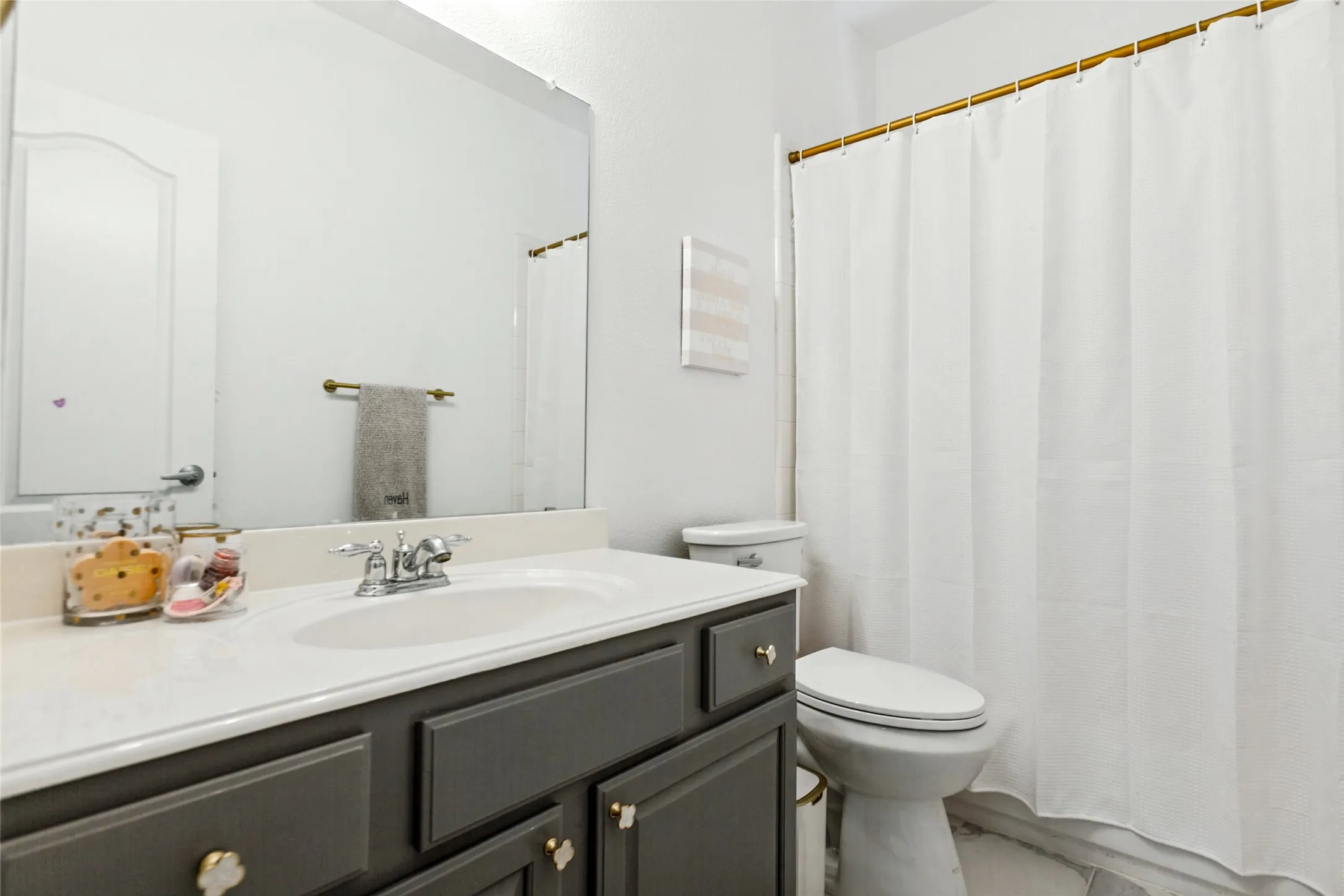 secondary bathroom with newly tiled floors, White vanity countertop with an integrated sink, dual-handle chrome faucet, and gray cabinetry