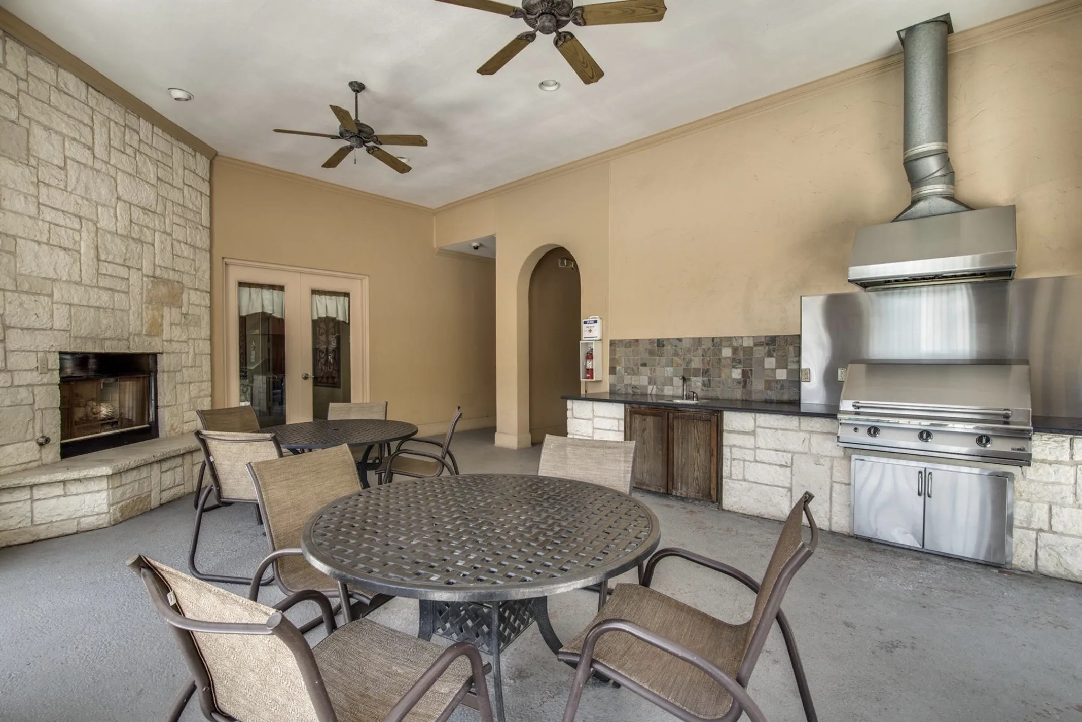Outdoor living area with a stone-clad fireplace and built-in stainless steel grill
