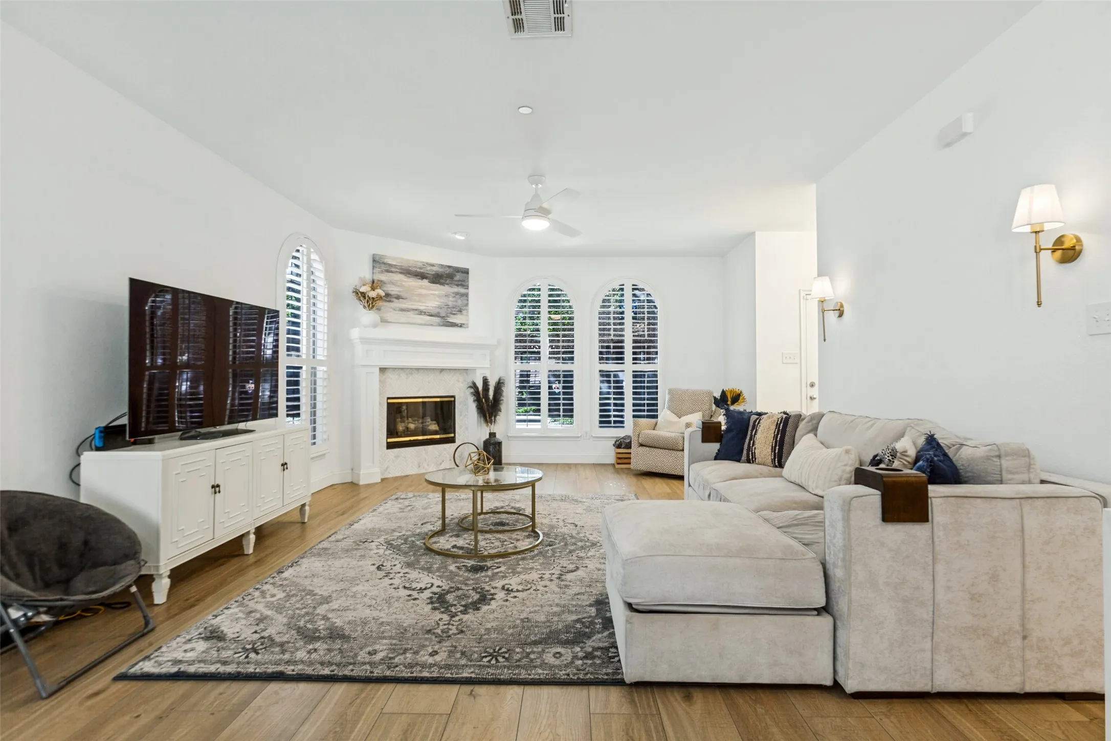 Wood-finish flooring throughout, white walls, and arched windows with shutters